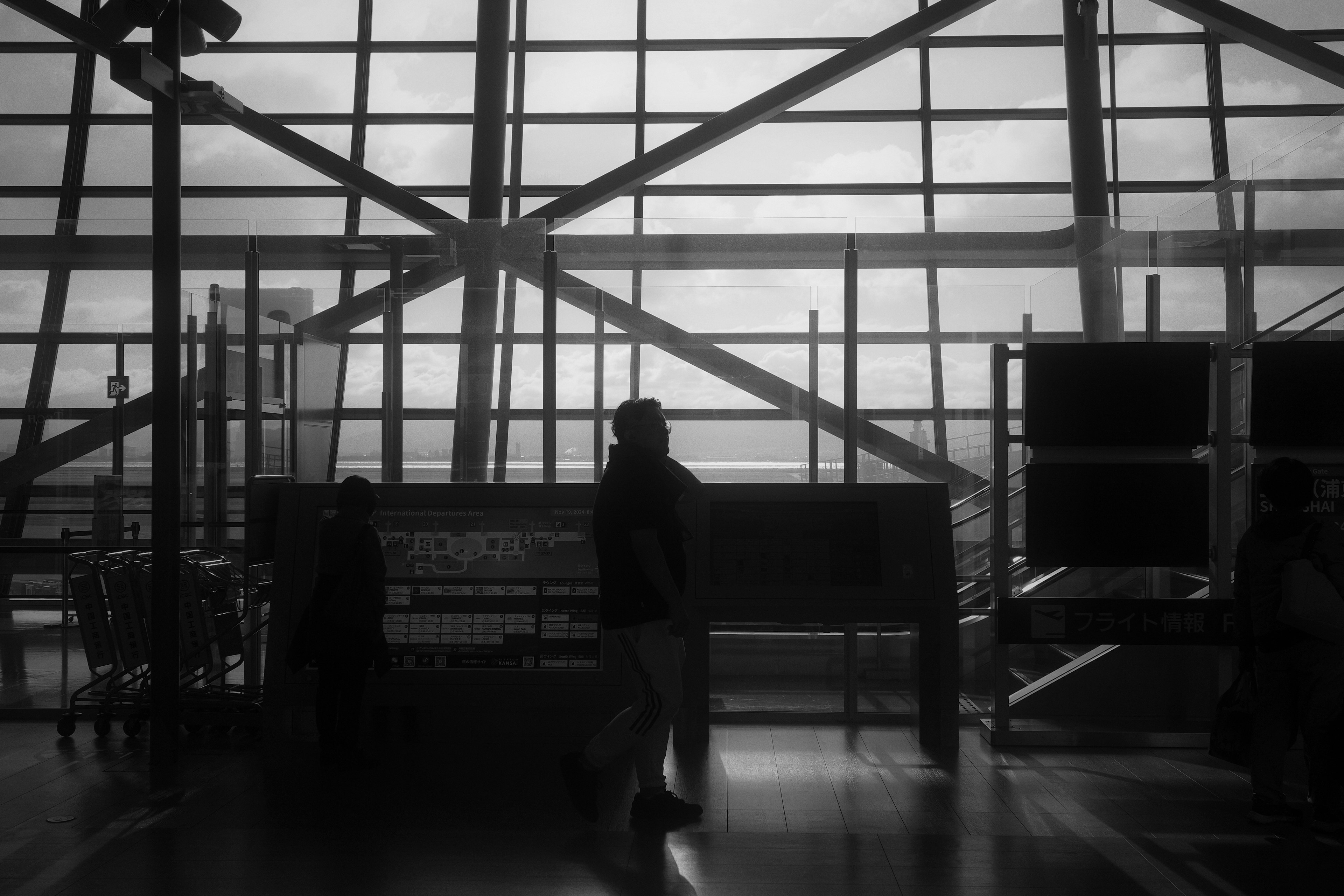 Silhouette of a person walking inside an airport with a monochrome background