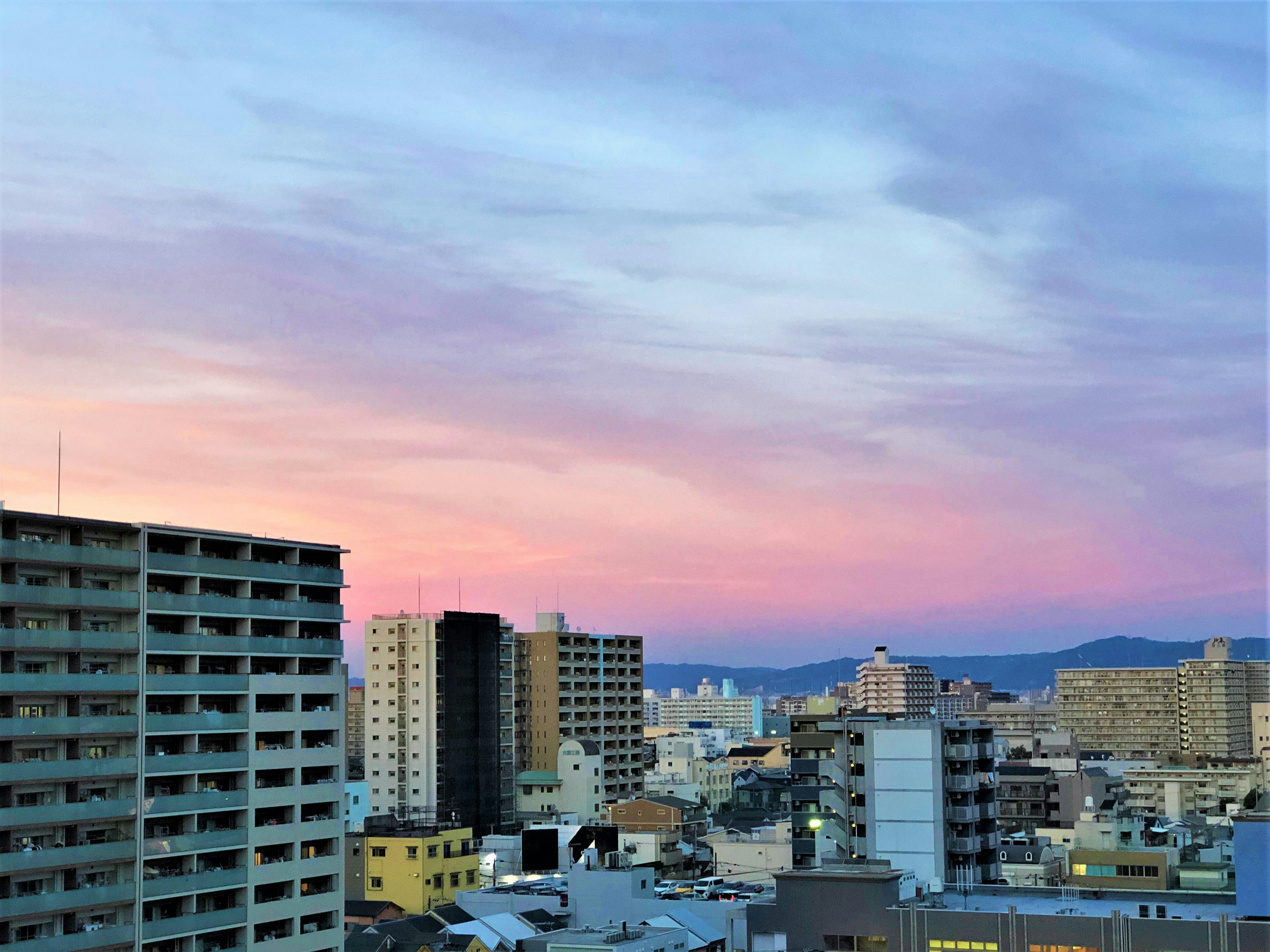 Cityscape at sunset featuring high-rise buildings and a colorful sky