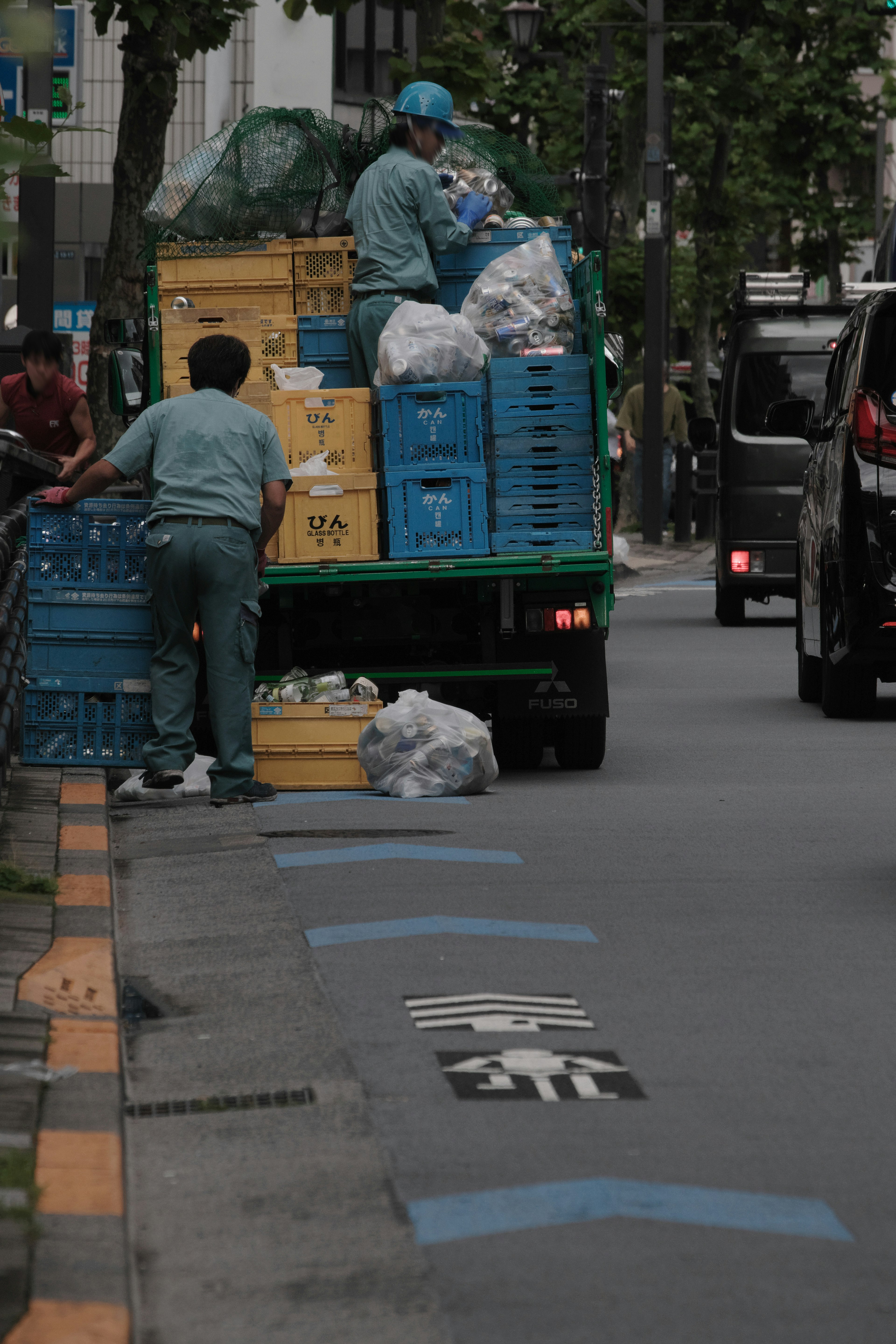 คนงานกำลังขนขยะขึ้นรถบรรทุกสีน้ำเงินเพื่อรีไซเคิล