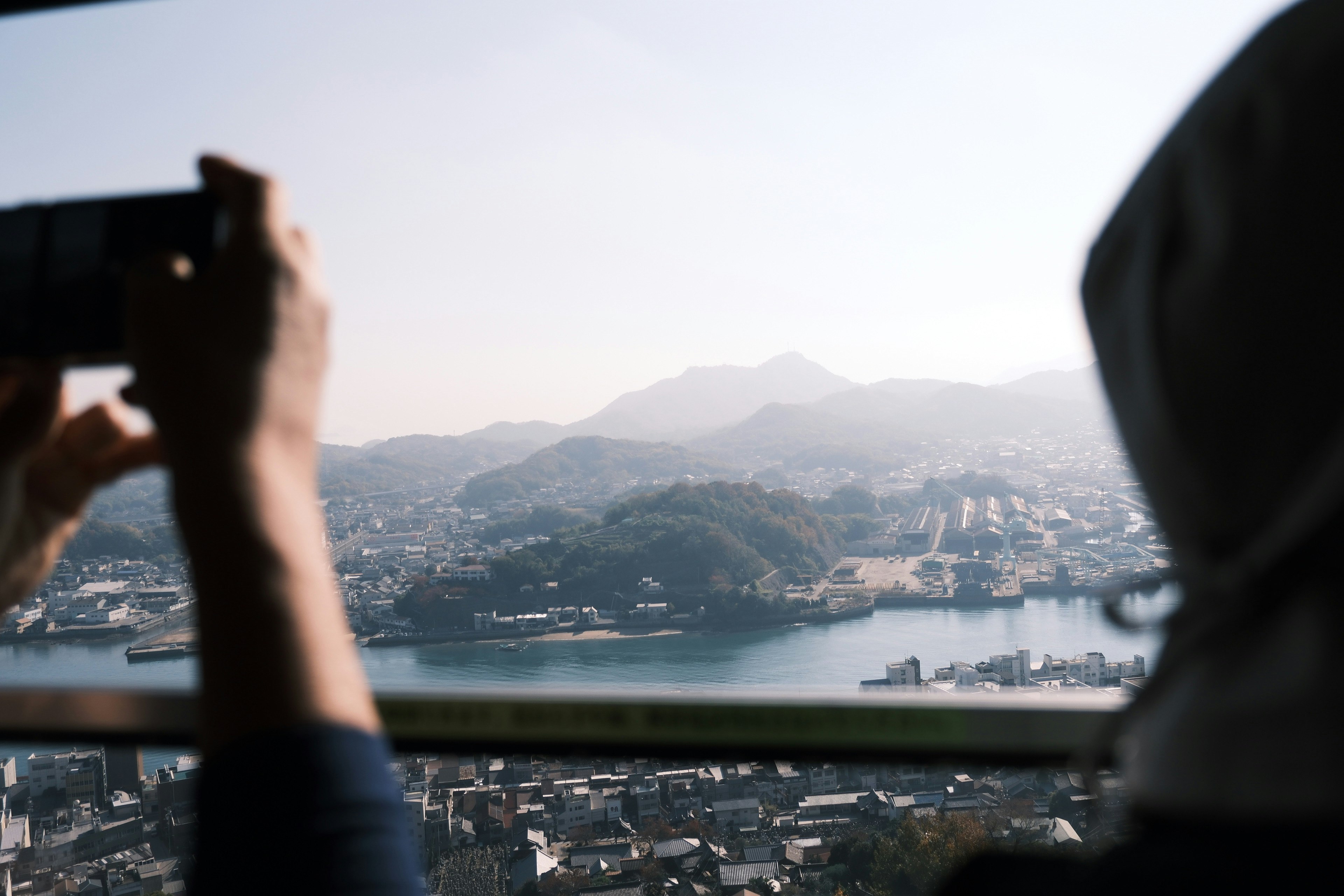 山と川を背景にスマートフォンで風景を撮影する人