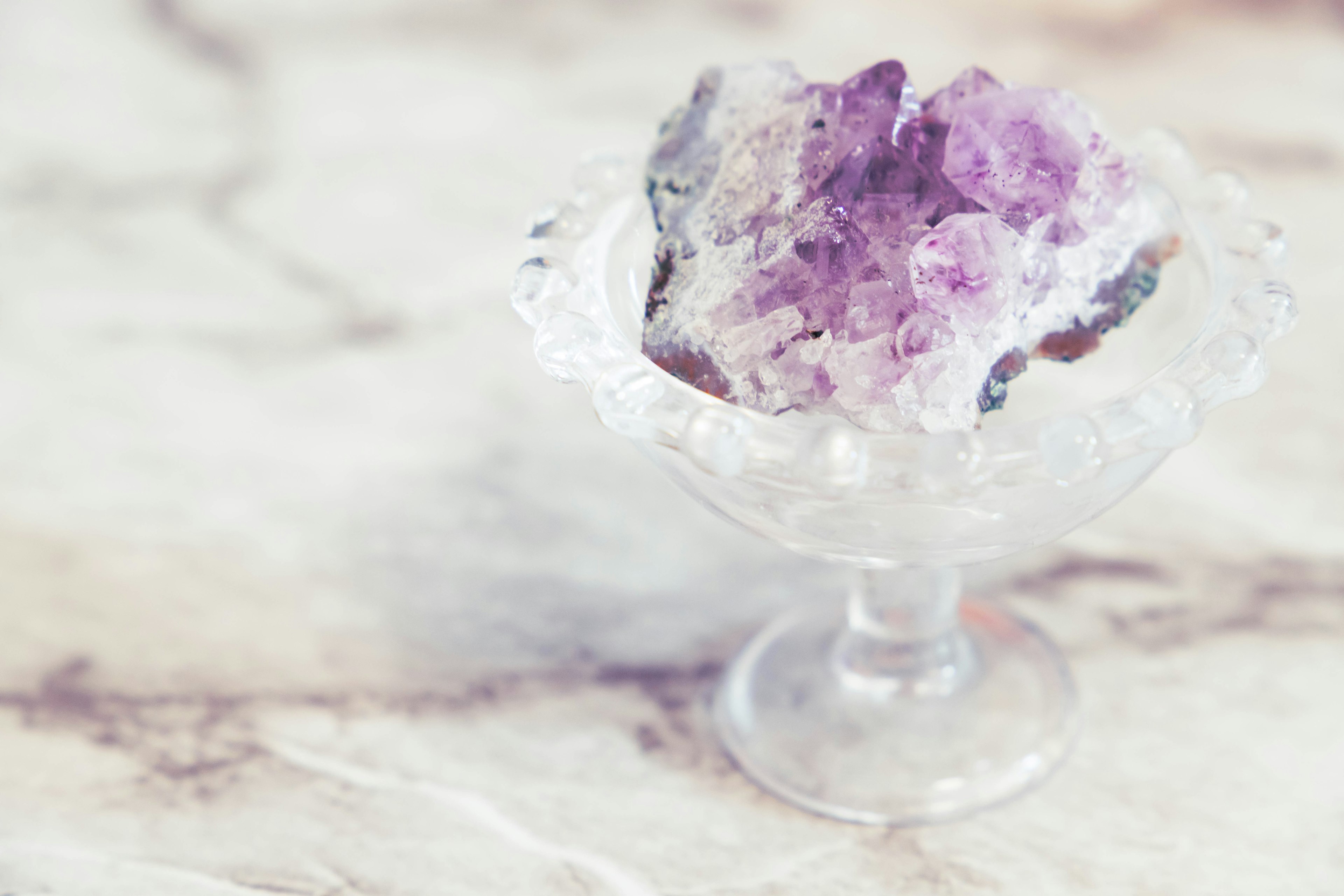 Amethyst crystal displayed in a glass dish