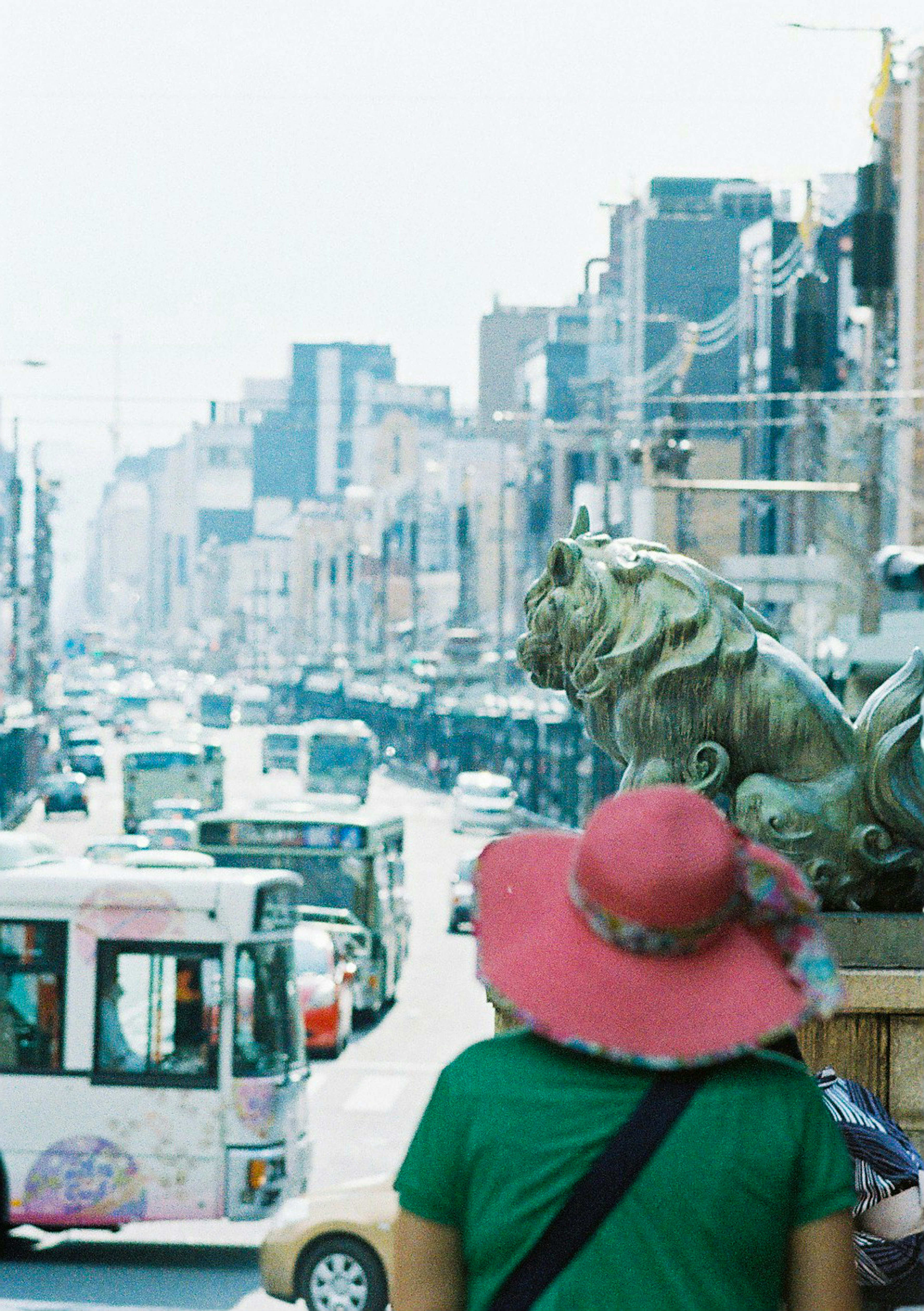 Rear view of a woman in a pink hat overlooking a busy street with traffic