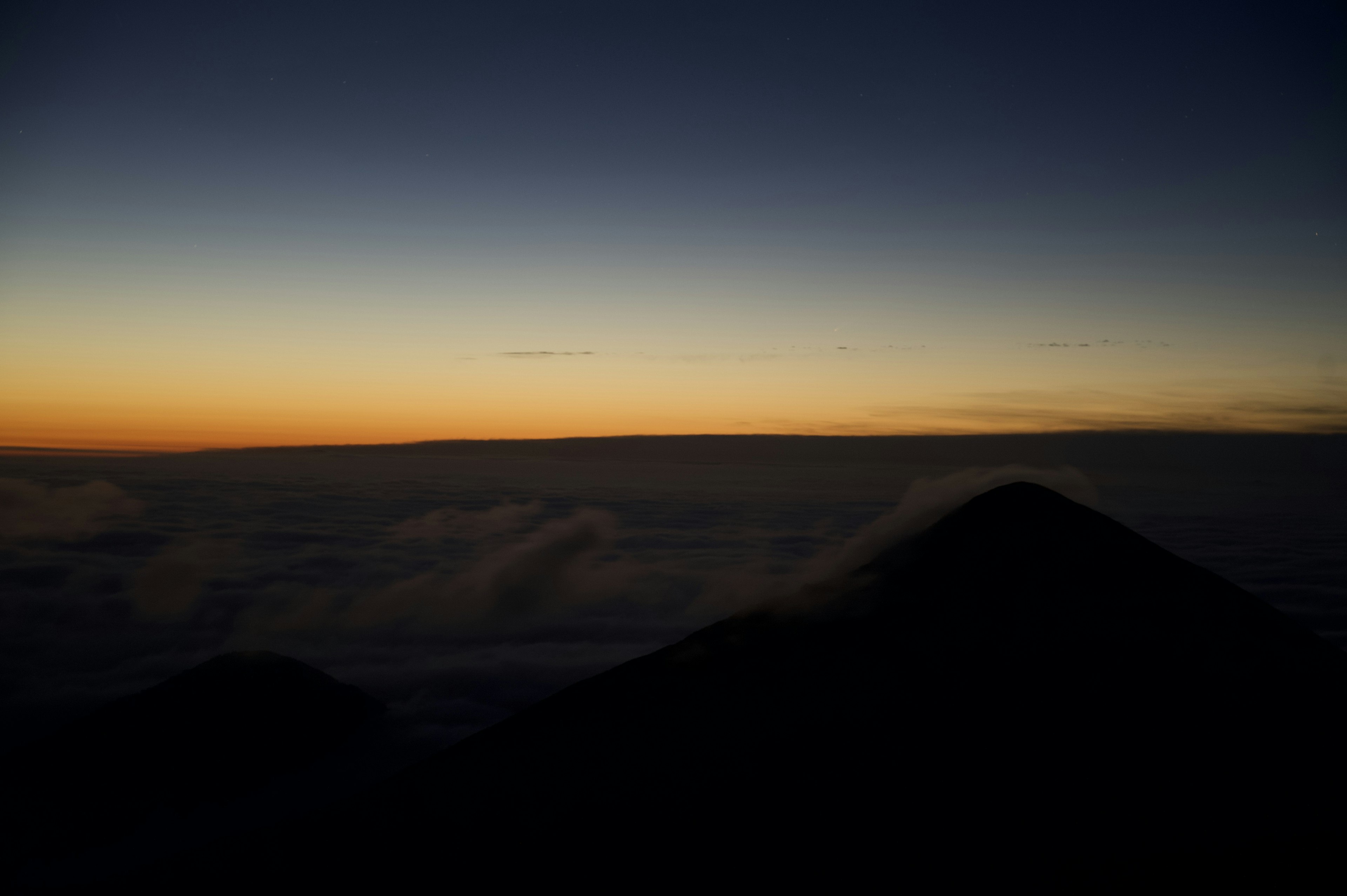 Silhouette di montagne sopra un mare di nuvole all'alba