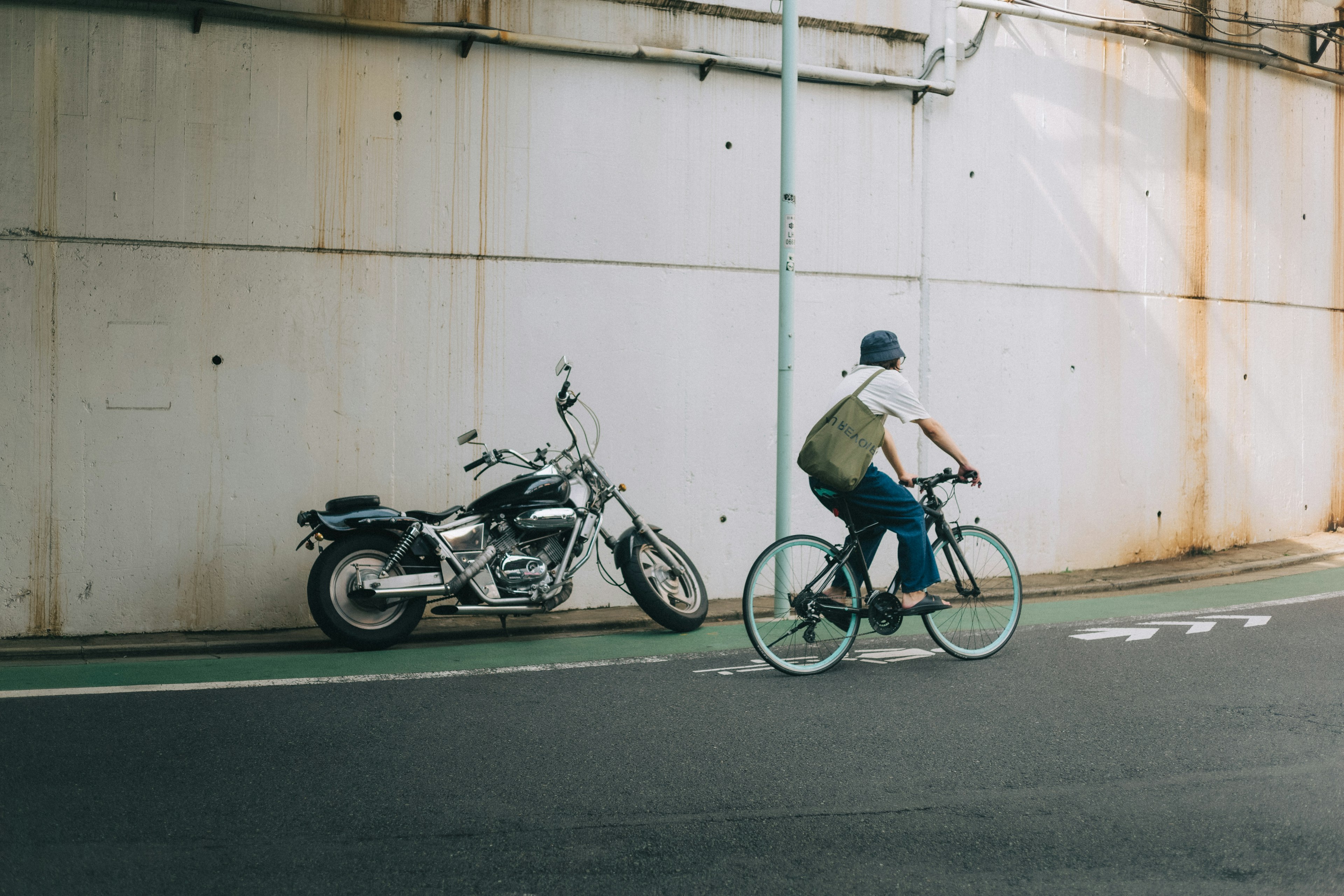 A person riding a bicycle next to a parked motorcycle against a wall