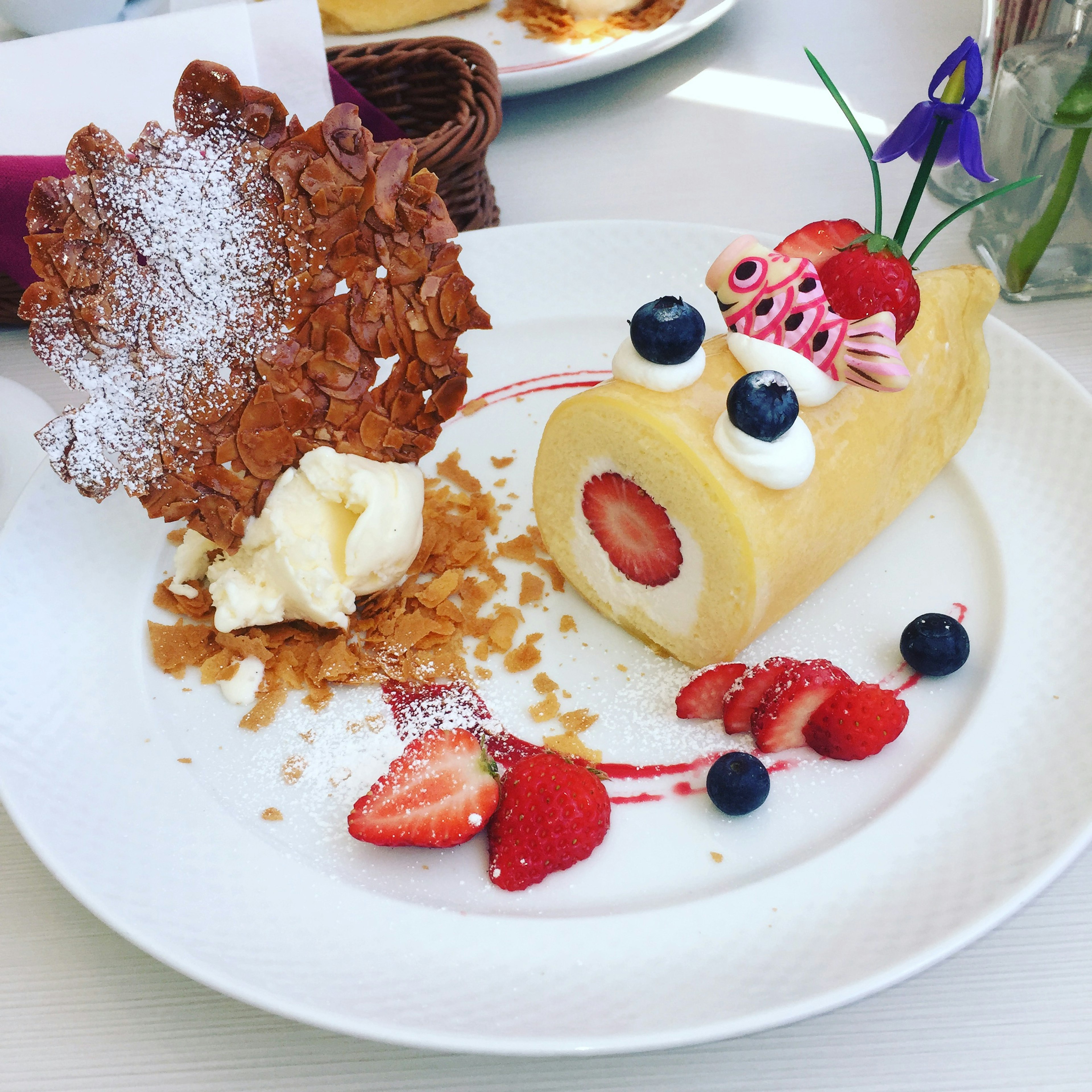 A dessert plate featuring a cream and strawberry roll cake shaped like a cute fish