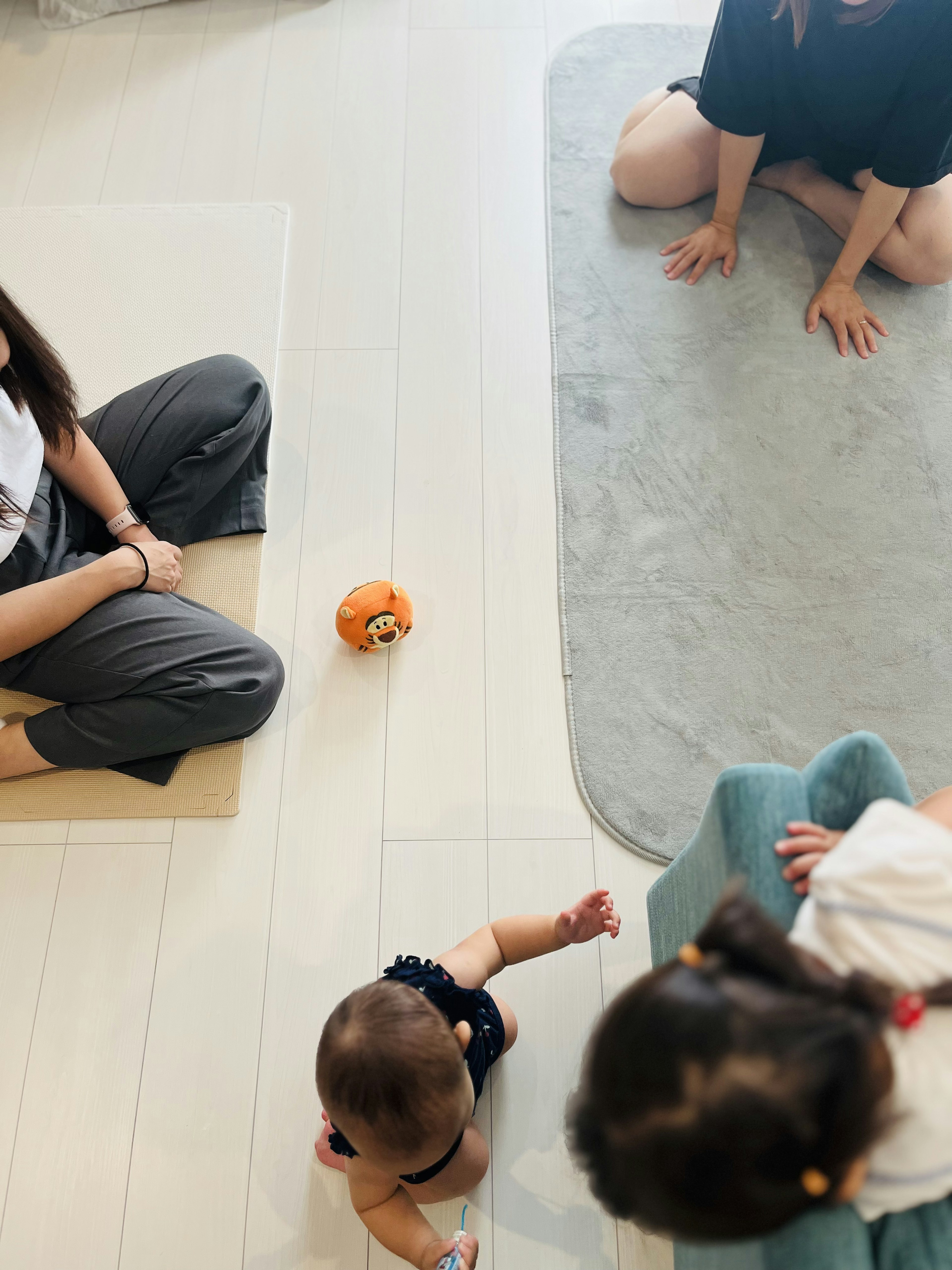 Vista di adulti seduti sul pavimento con un bambino che striscia e un giocattolo