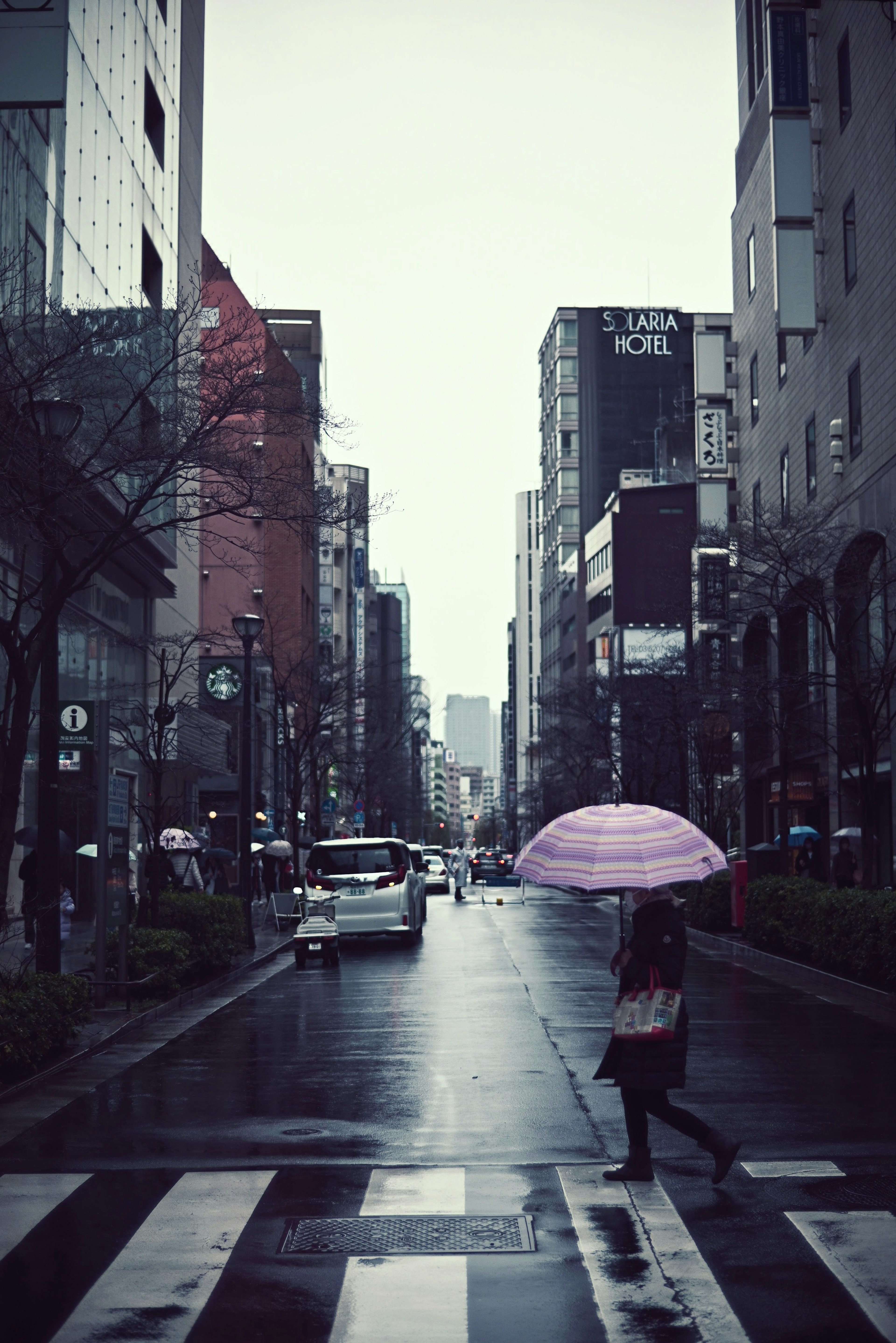 Personne avec un parapluie rose marchant sous la pluie dans une rue de la ville