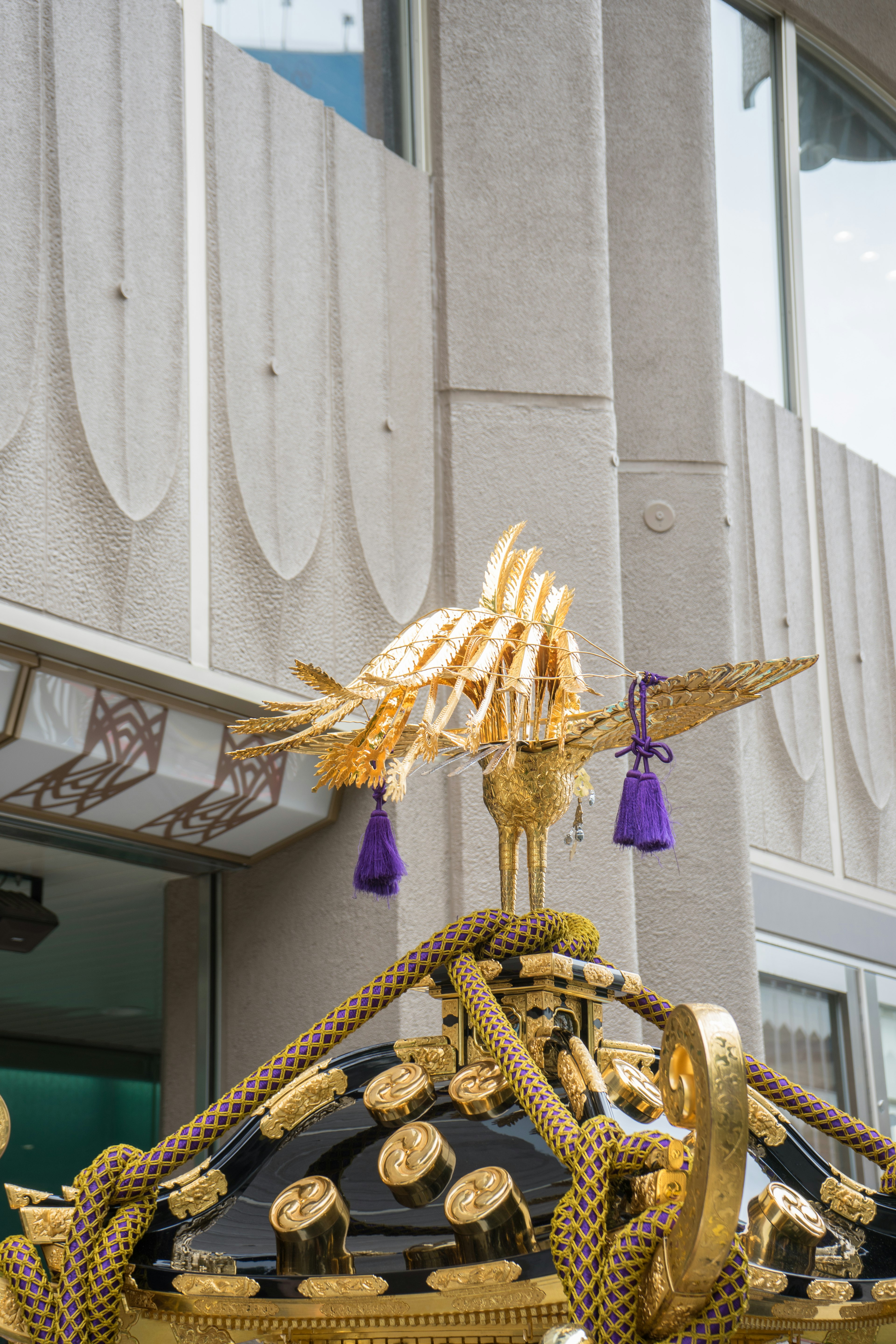 Figura decorativa de pájaro dorado en la parte superior de un santuario portátil tradicional