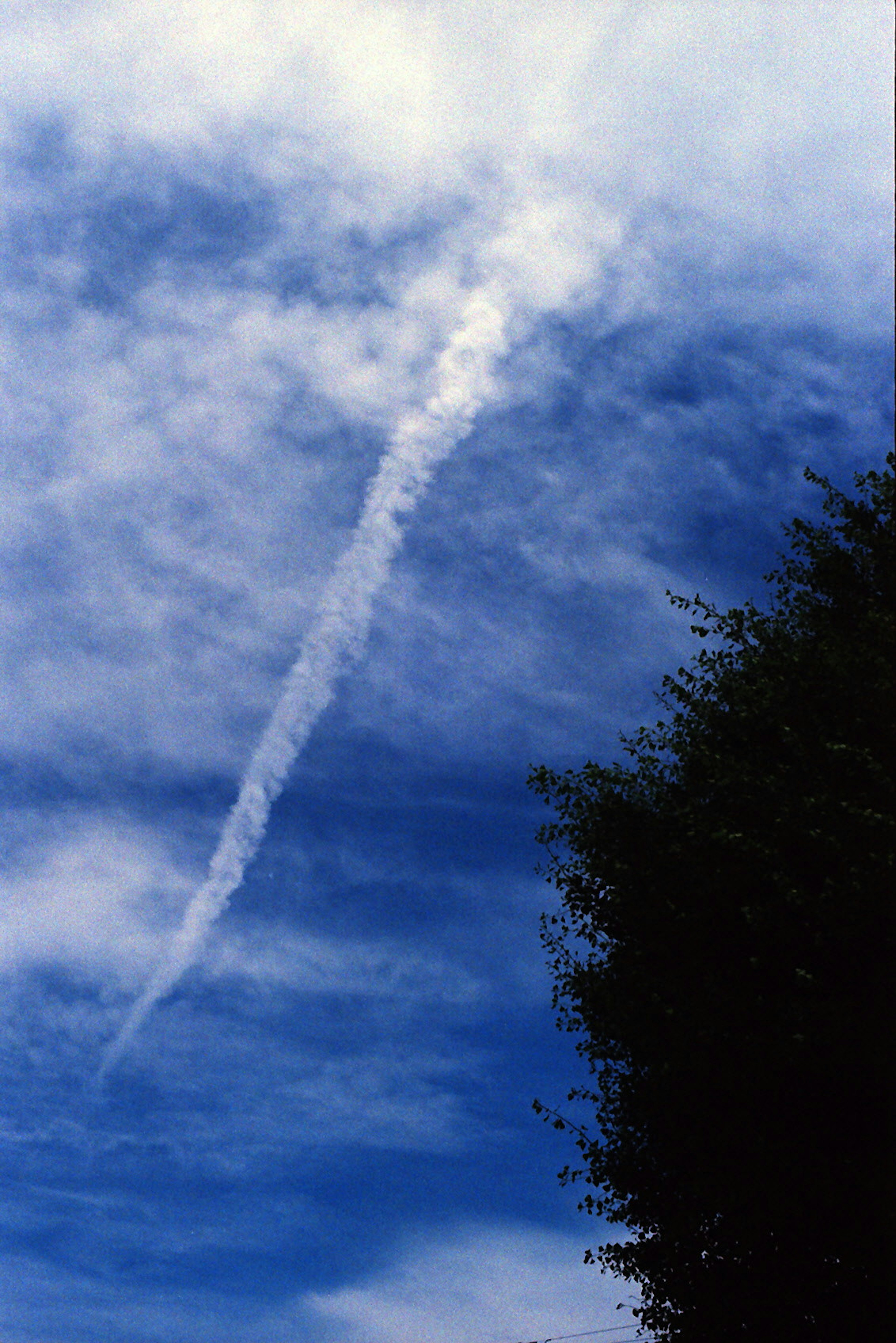 Una scia bianca si estende attraverso un cielo blu con nuvole