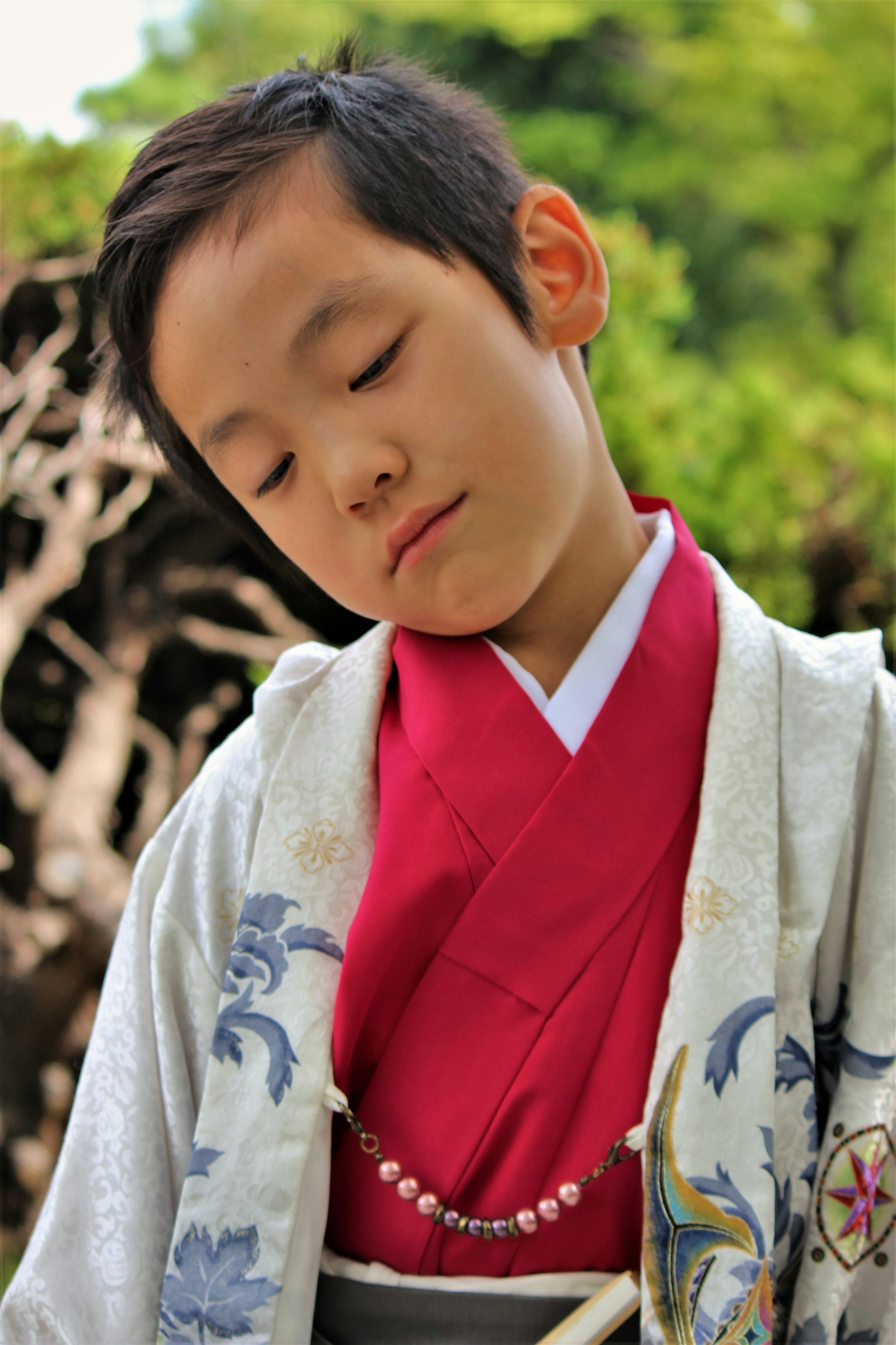 A young boy wearing a red kimono with a serene expression