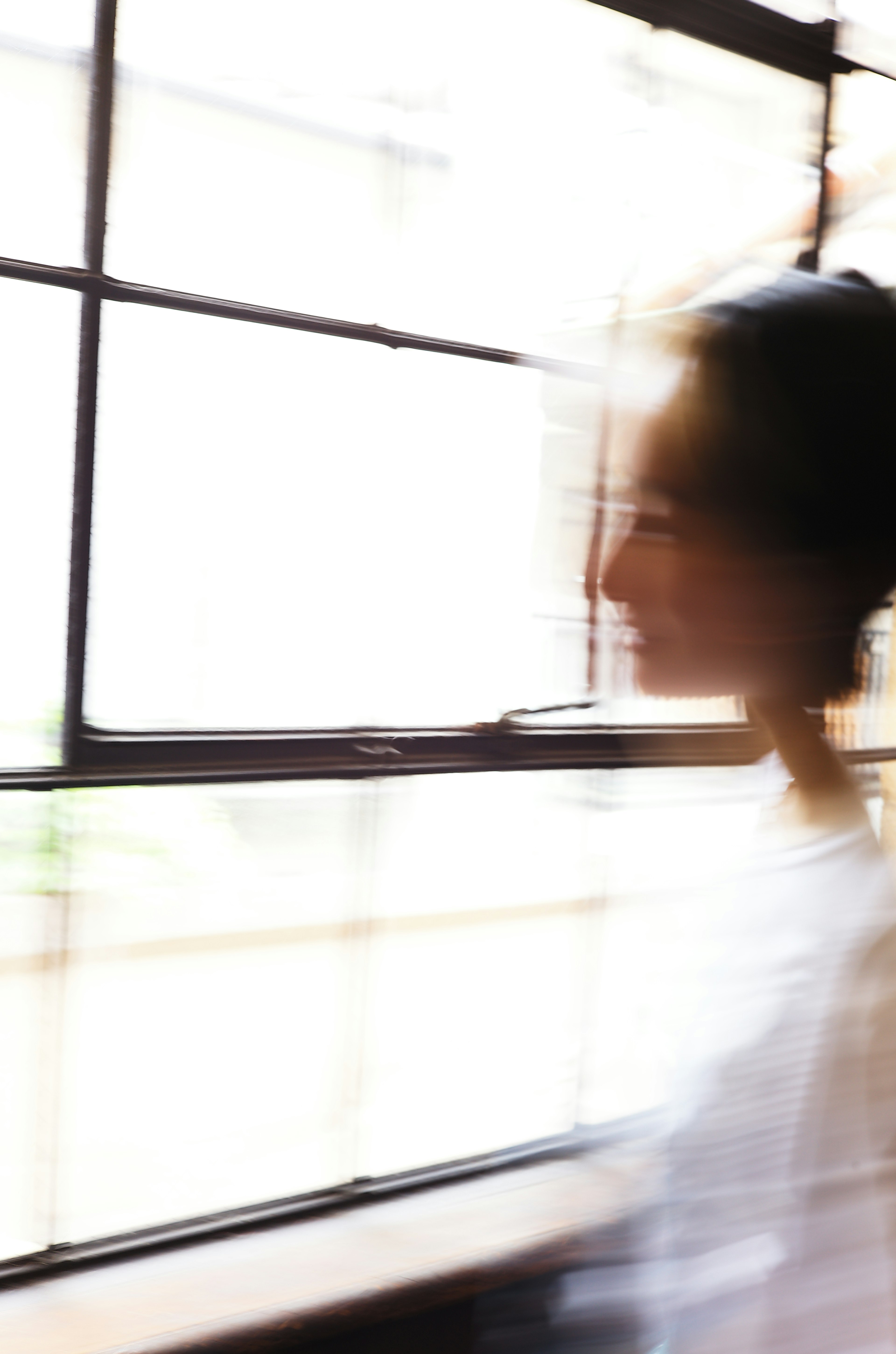 Silhouette sfocata di una donna che si muove vicino a una finestra