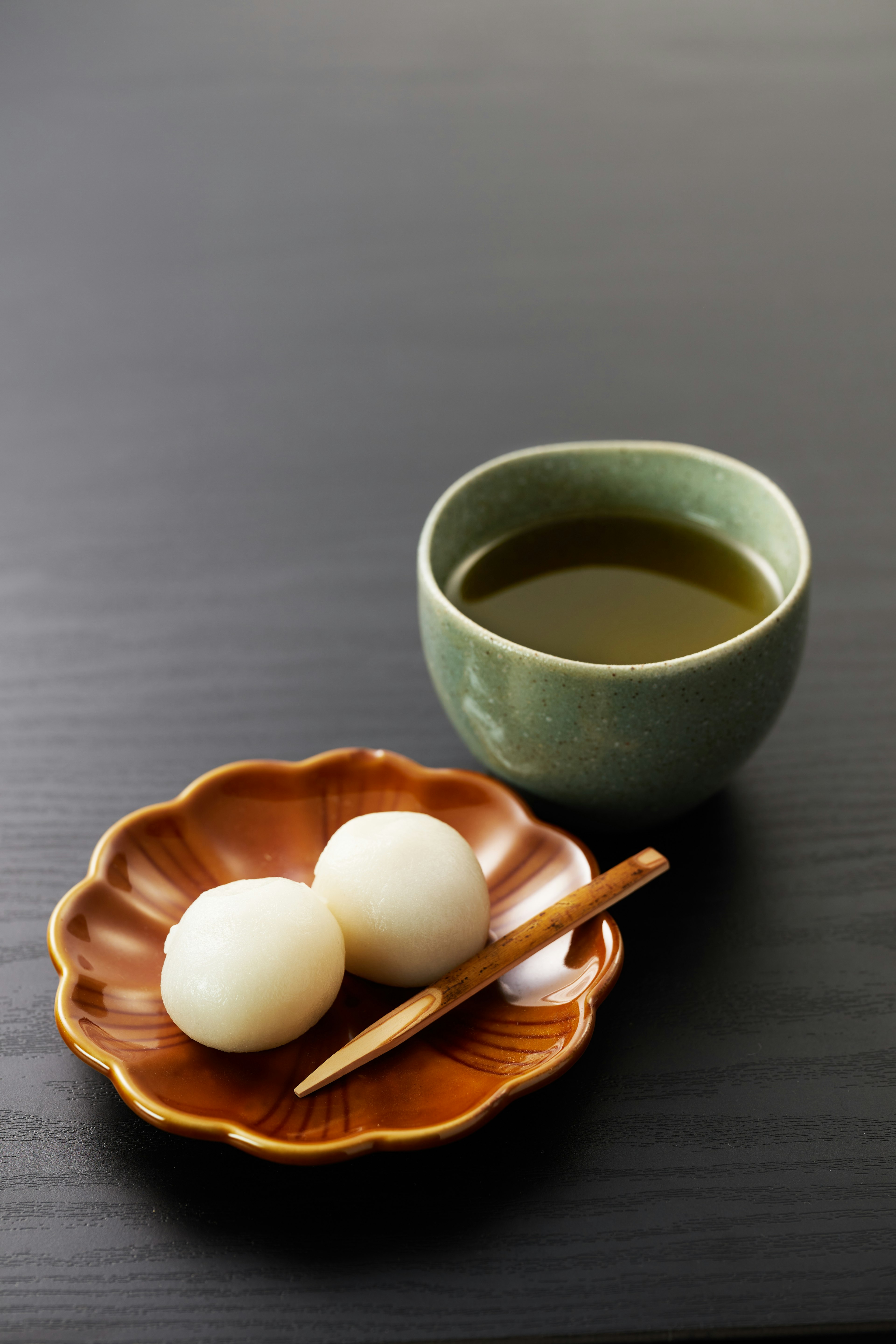 A simple Japanese snack with a tea cup and a plate of dango on a table