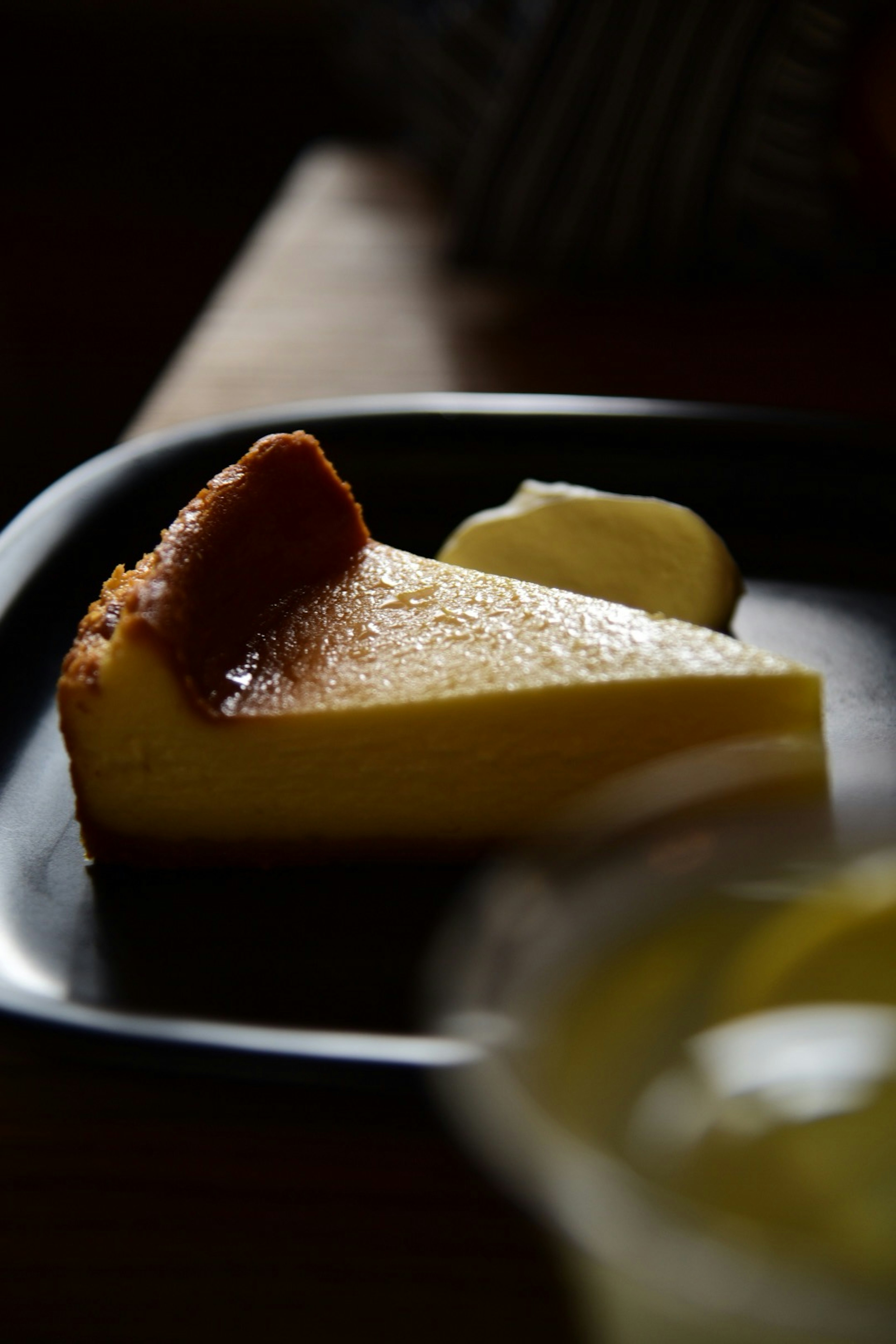 Stück Käsekuchen mit Butter auf einem schwarzen Teller