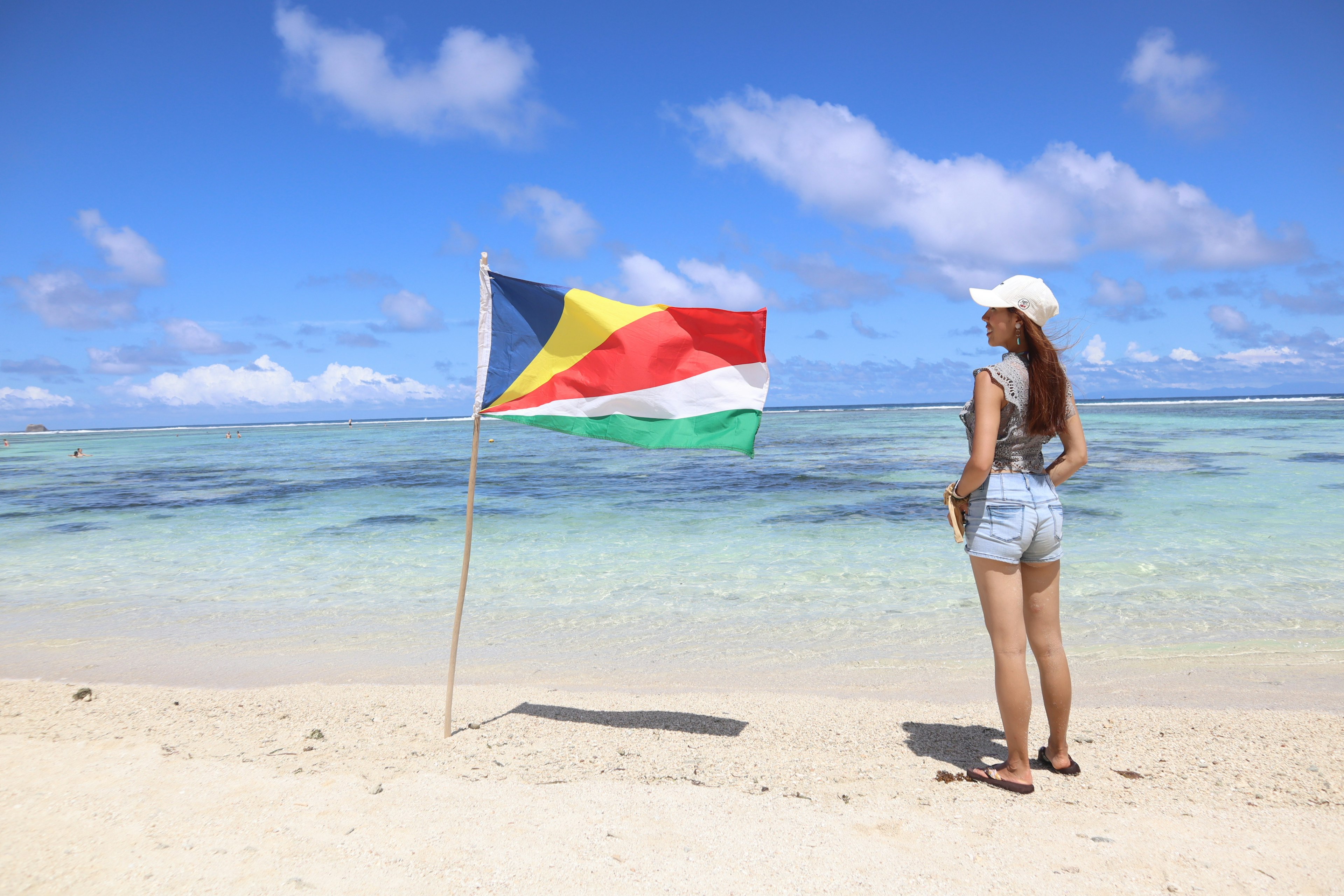 Woman standing on a beach with the Seychelles flag waving in the breeze