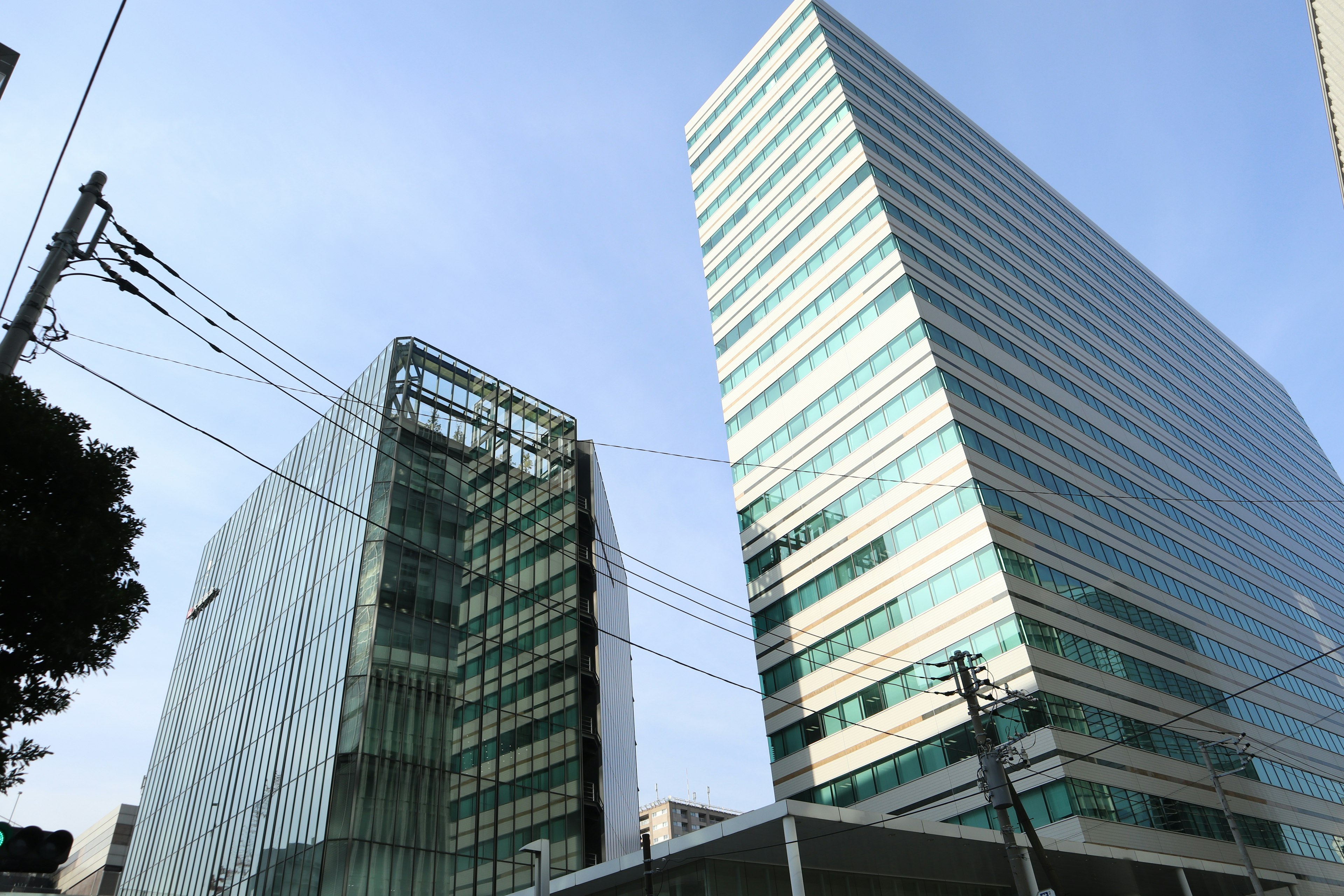 Gedung modern tinggi dengan fasad kaca di bawah langit biru yang cerah