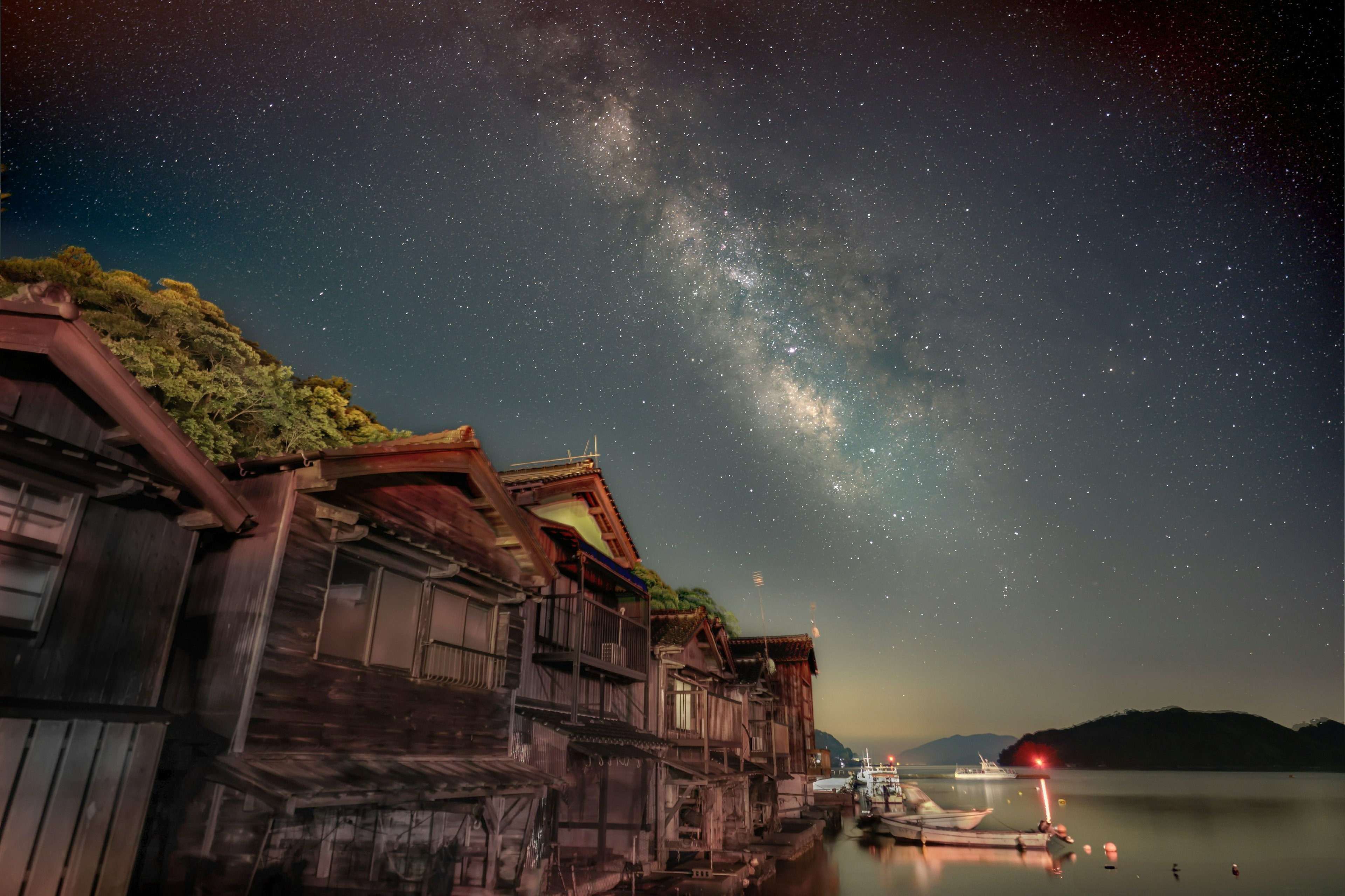 星空の下にある古い家屋と静かな湖の風景