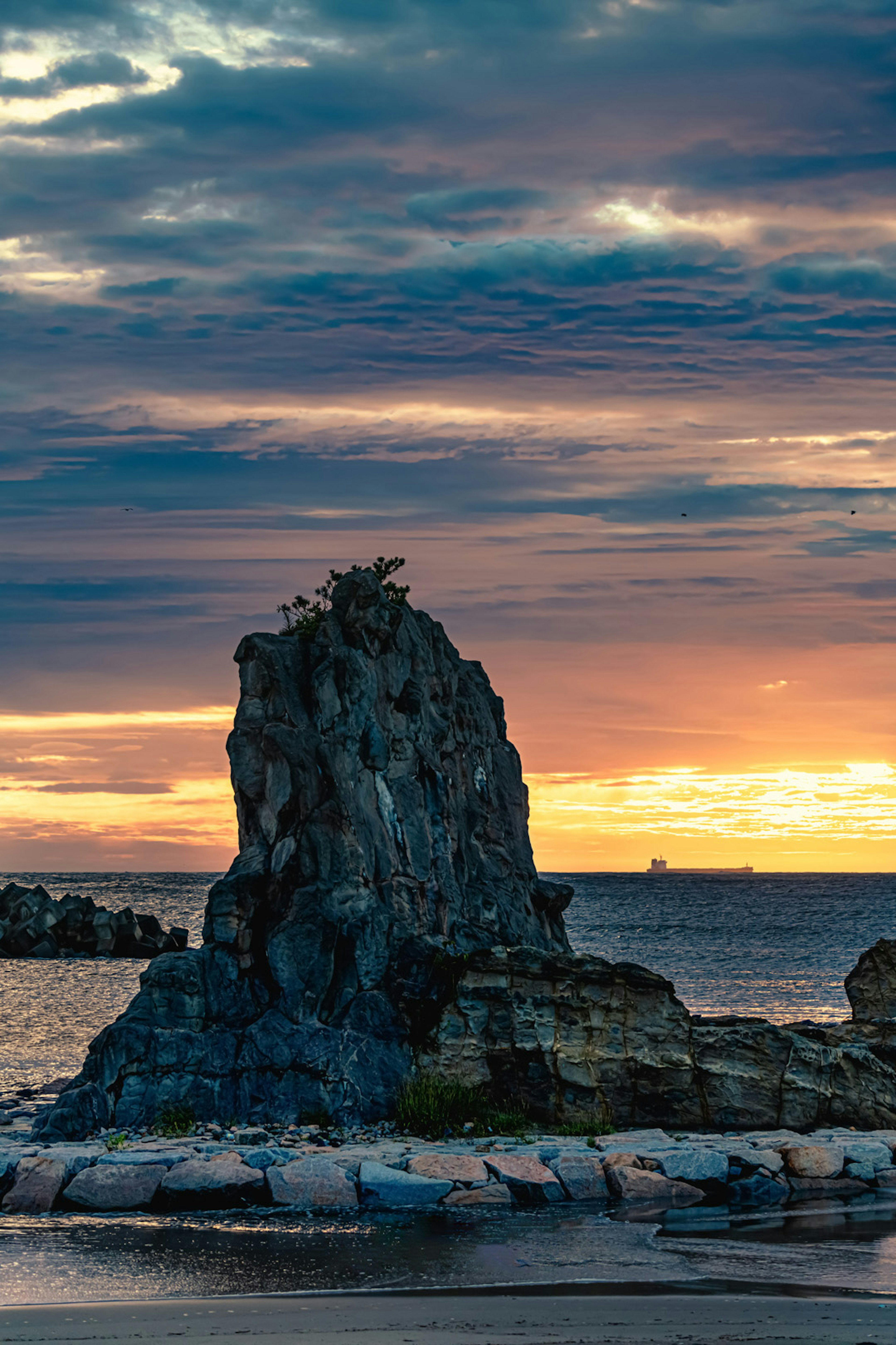 Formazione rocciosa costiera sotto un cielo al tramonto mozzafiato