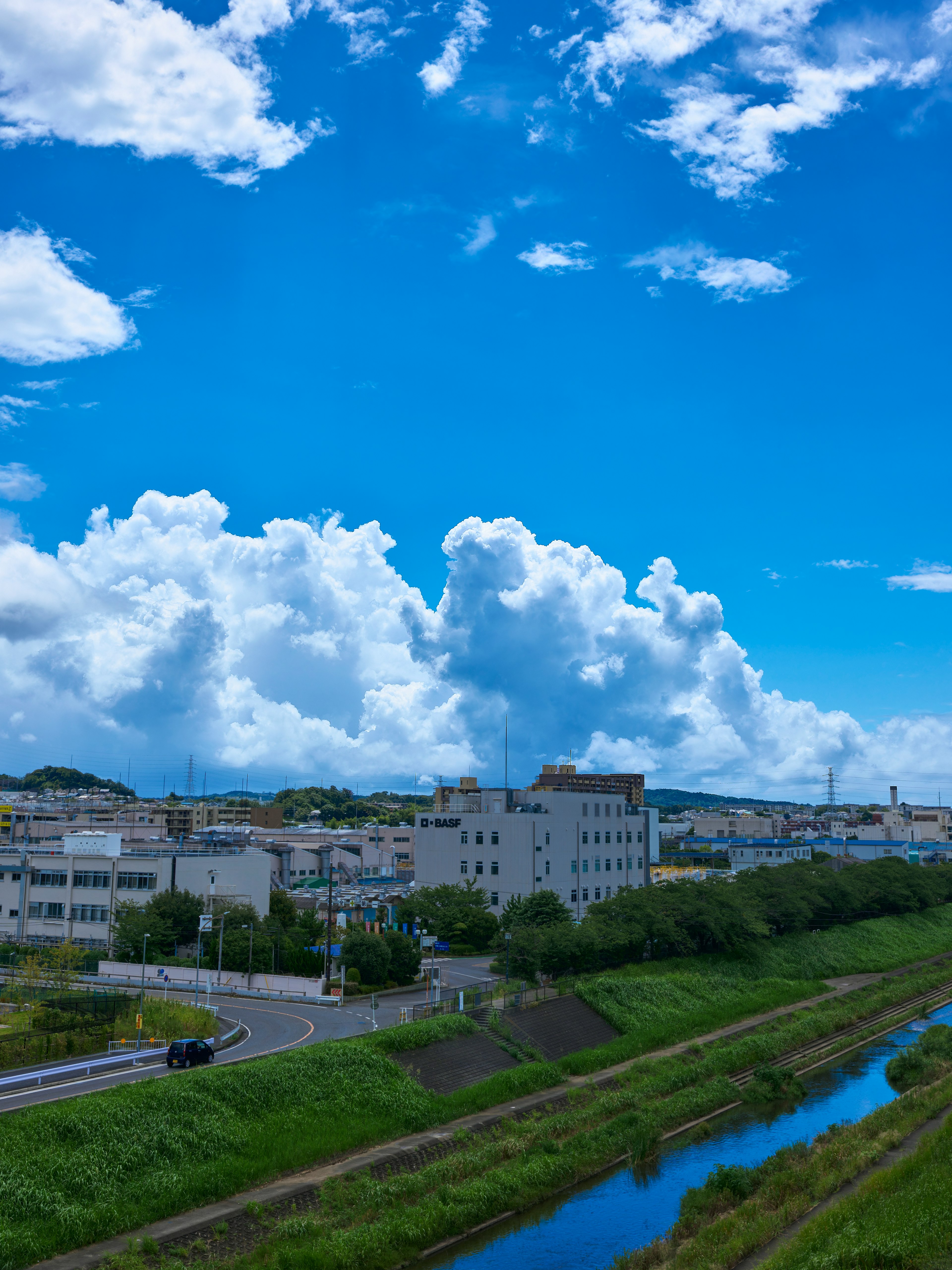 Vista panoramica di un fiume con rive verdi sotto un cielo azzurro e nuvole bianche