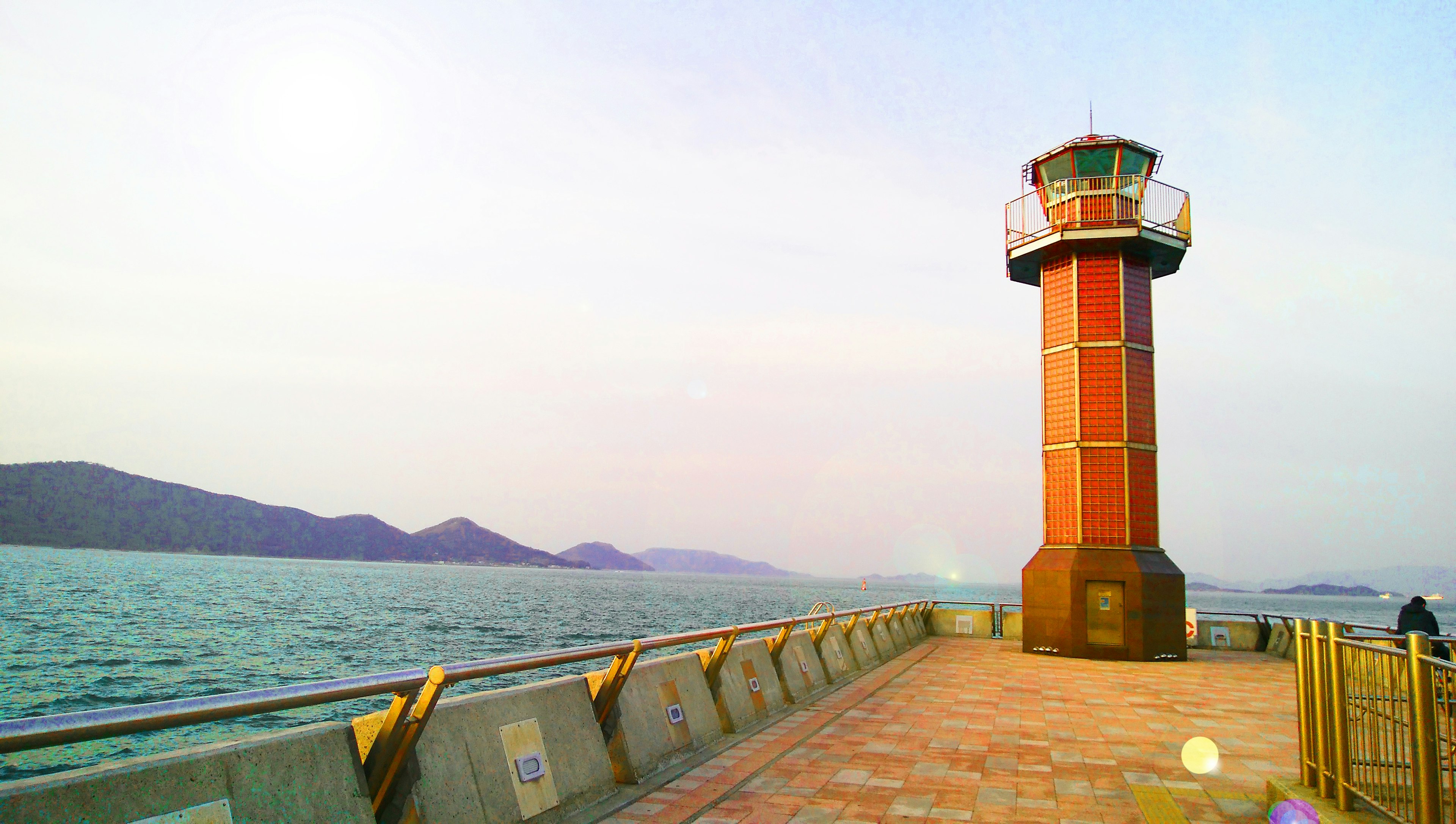 Red lighthouse by the sea with visible waves