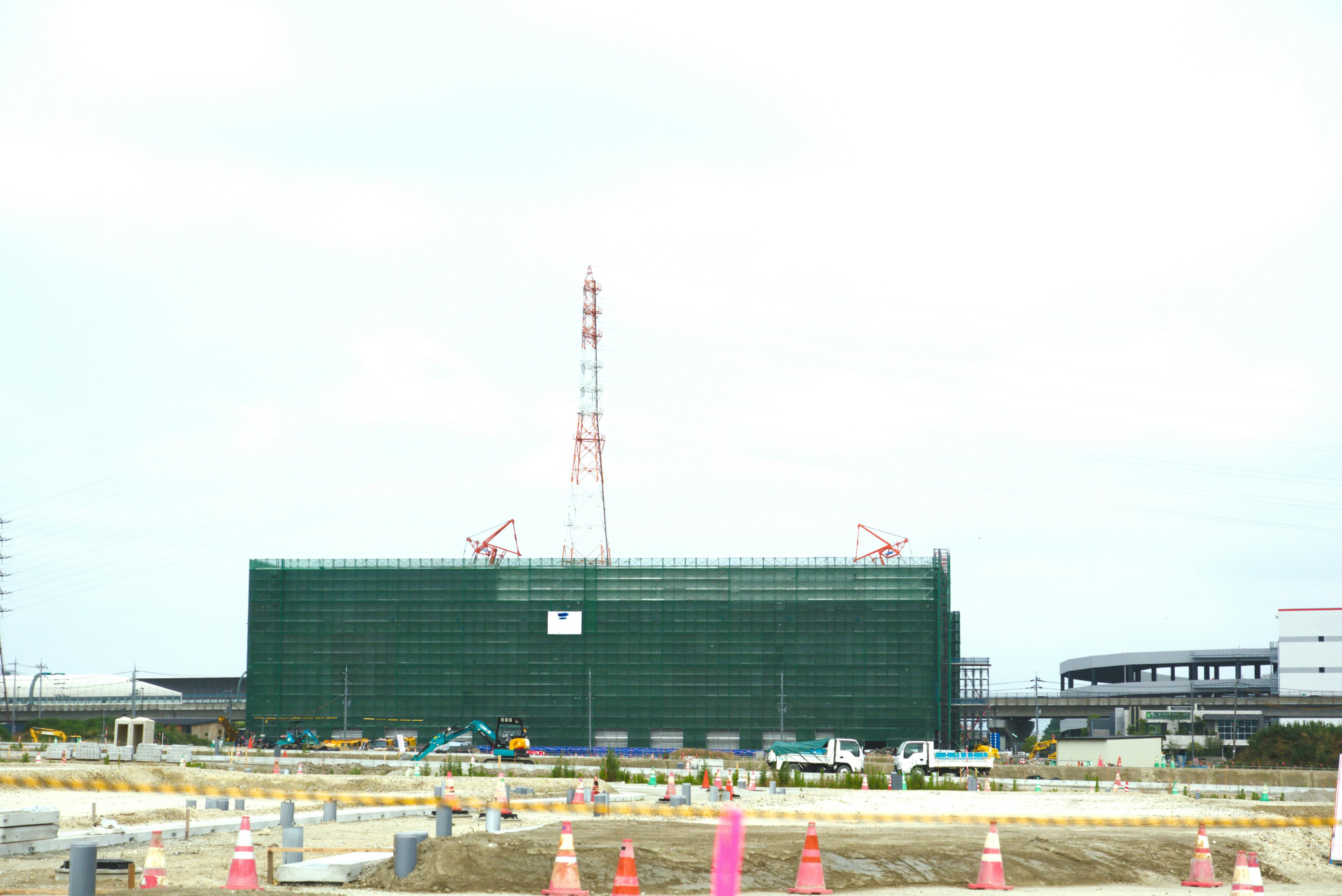 View of a construction site with a green-wrapped building and cranes