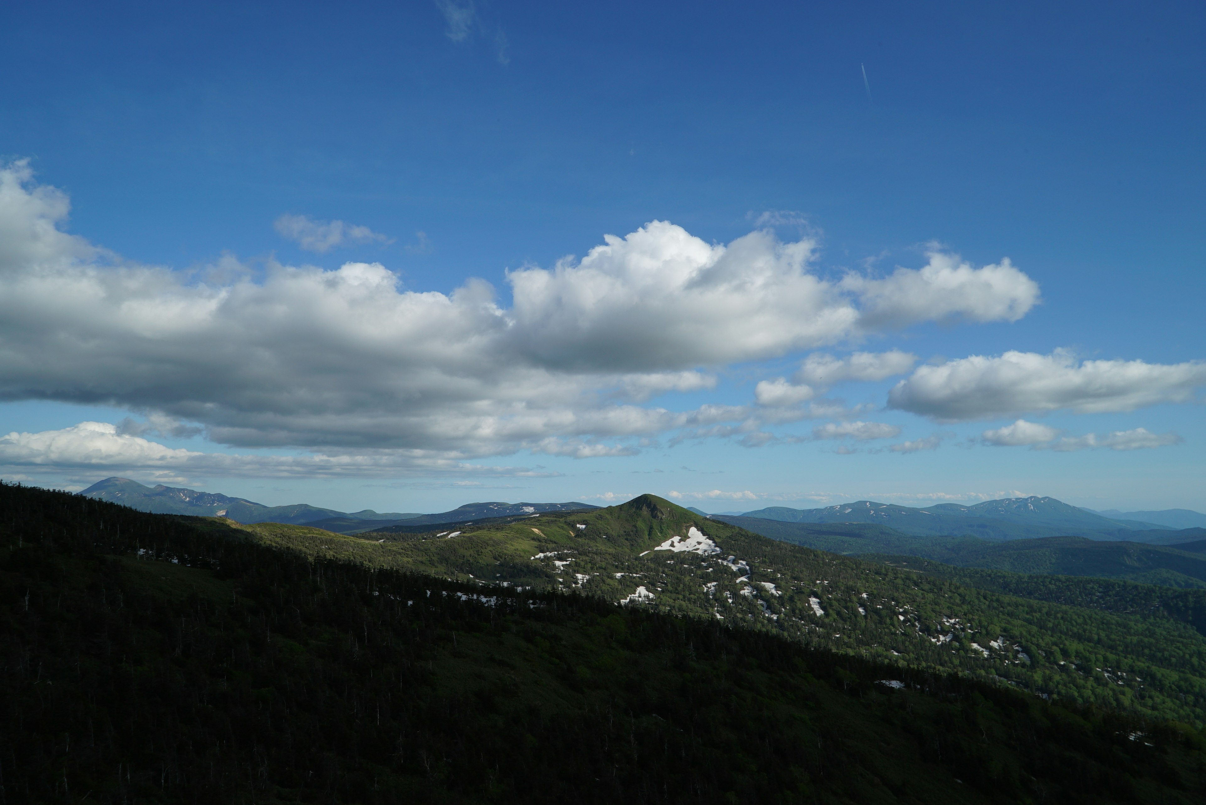 青空と白い雲が広がる山の風景 緑の丘と遠くの山々が見える