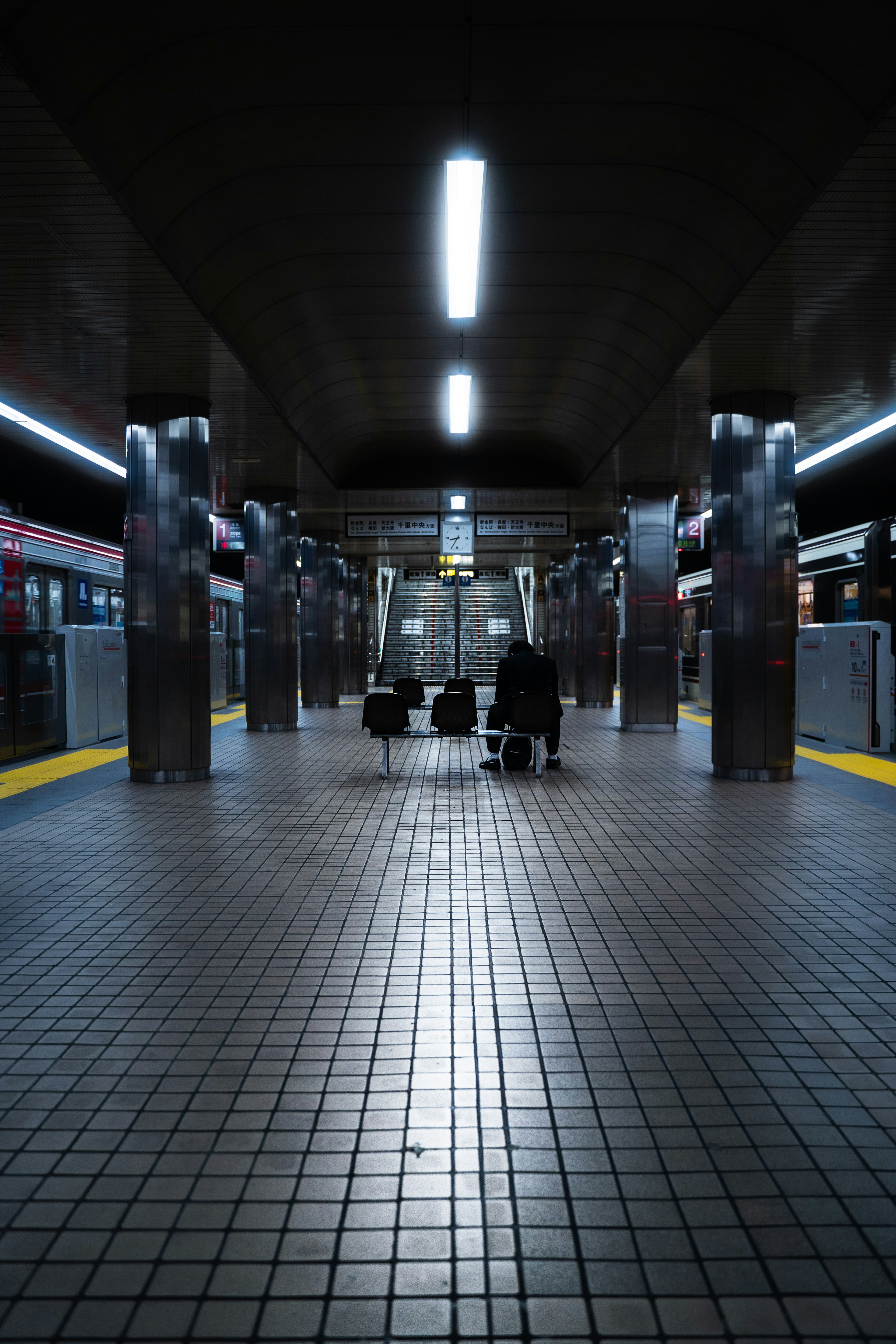 Interior de estación de metro con suelo de baldosas iluminación brillante y personas sentadas