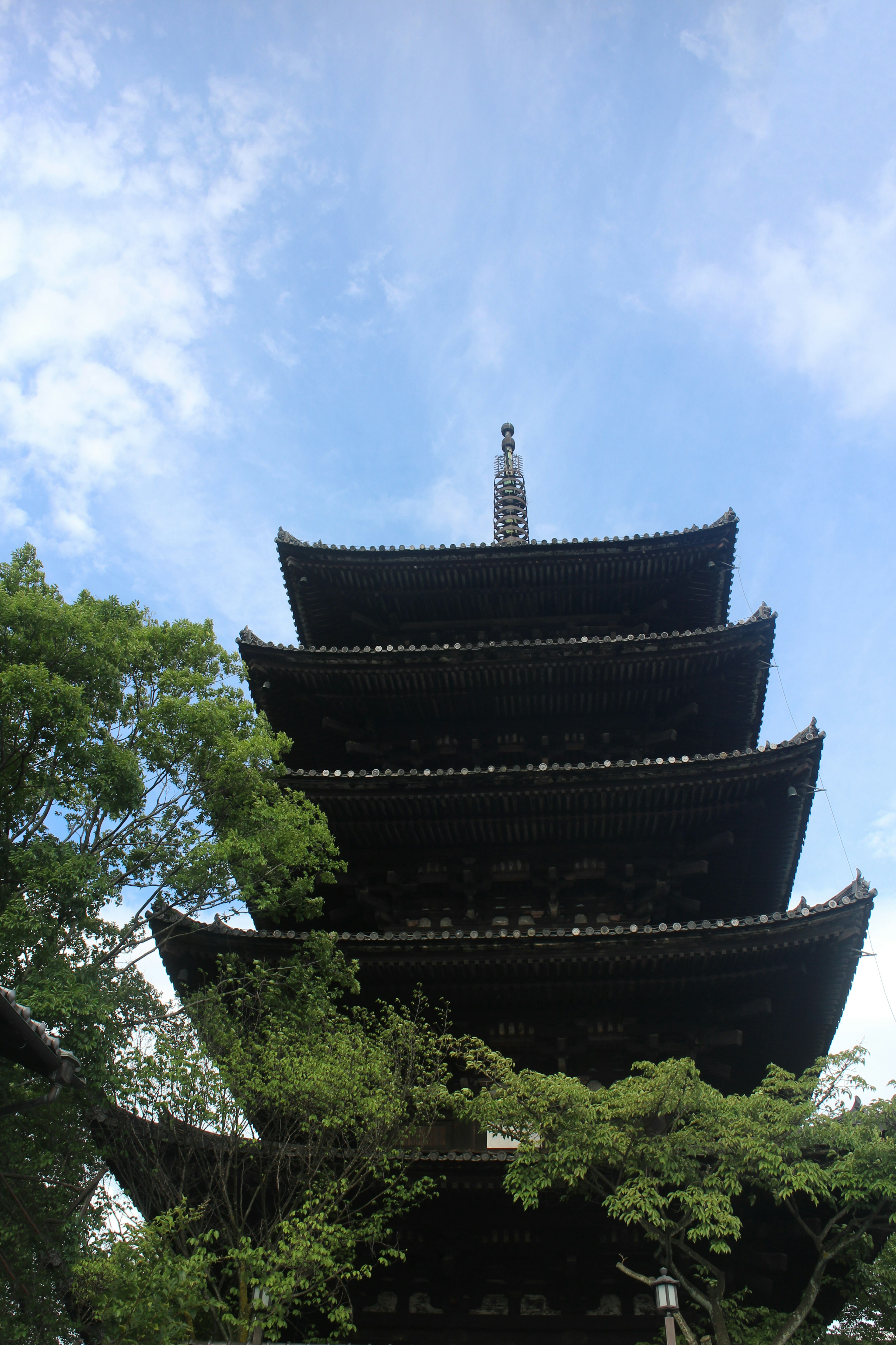 Fünfstöckige Pagode umgeben von grünen Bäumen und blauem Himmel