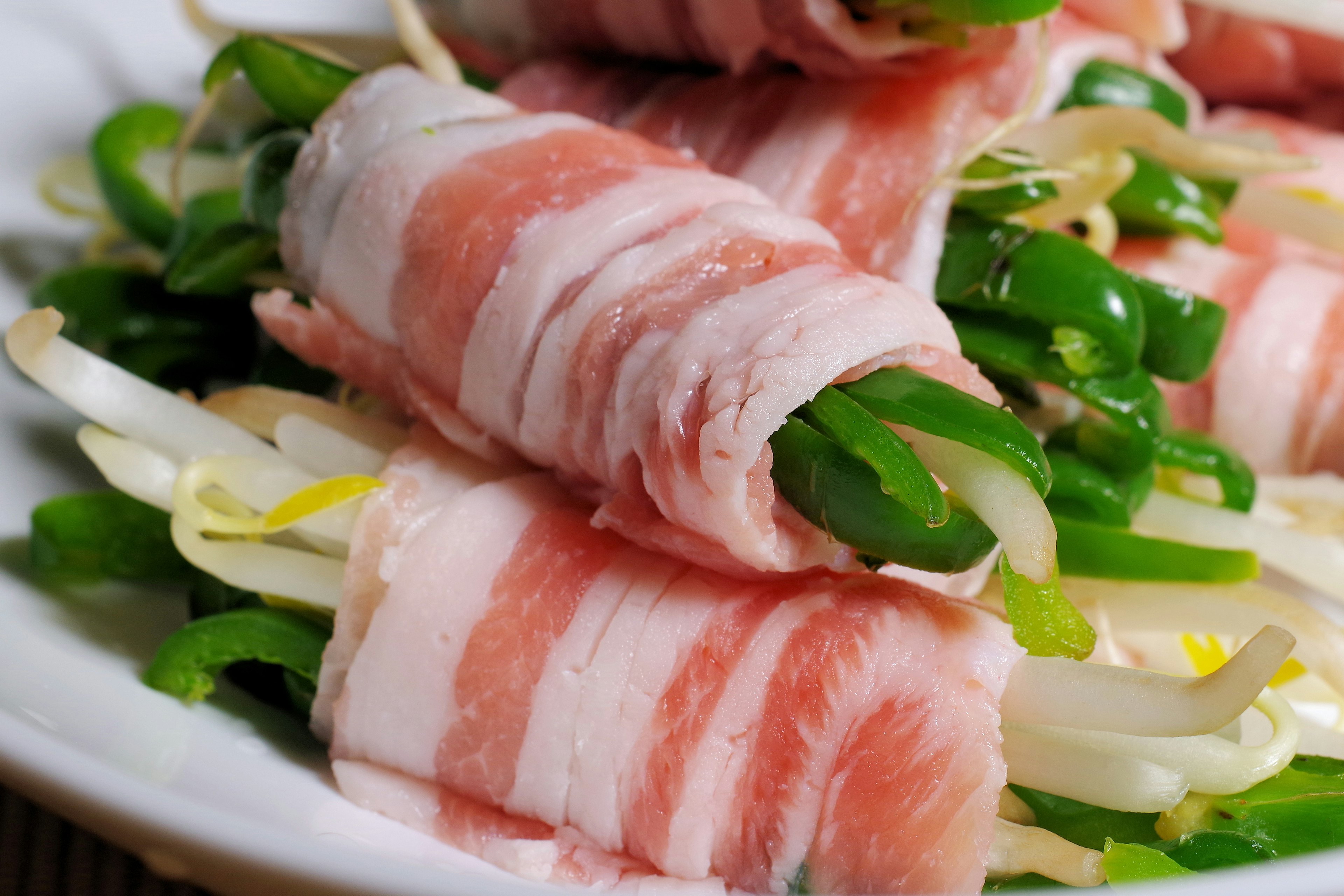 Piatto di verdure fresche avvolte in fette sottili di maiale