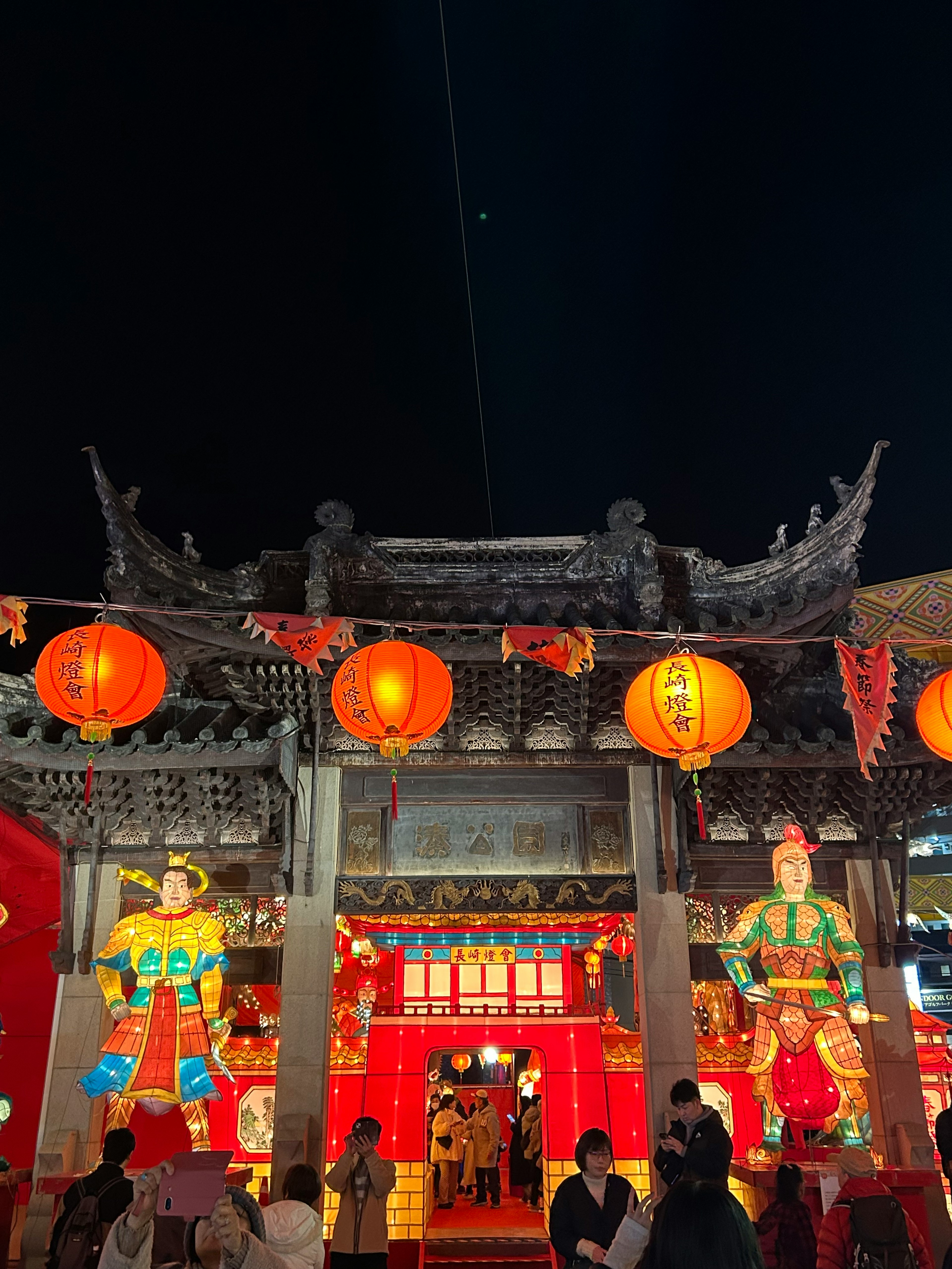 Exterior de un templo tradicional adornado con faroles durante un festival nocturno