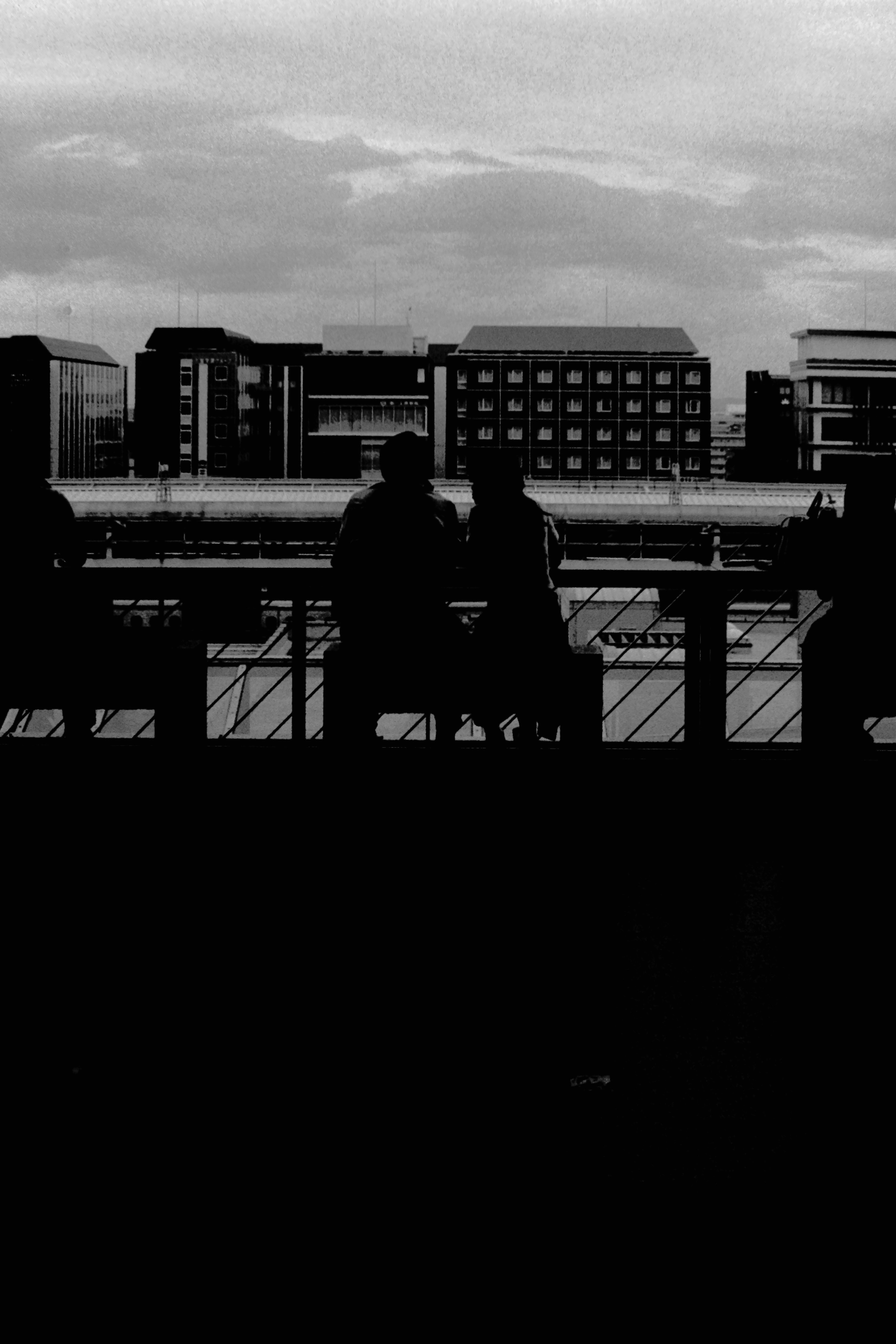 Siluetas de personas sentadas frente a un paisaje urbano en blanco y negro