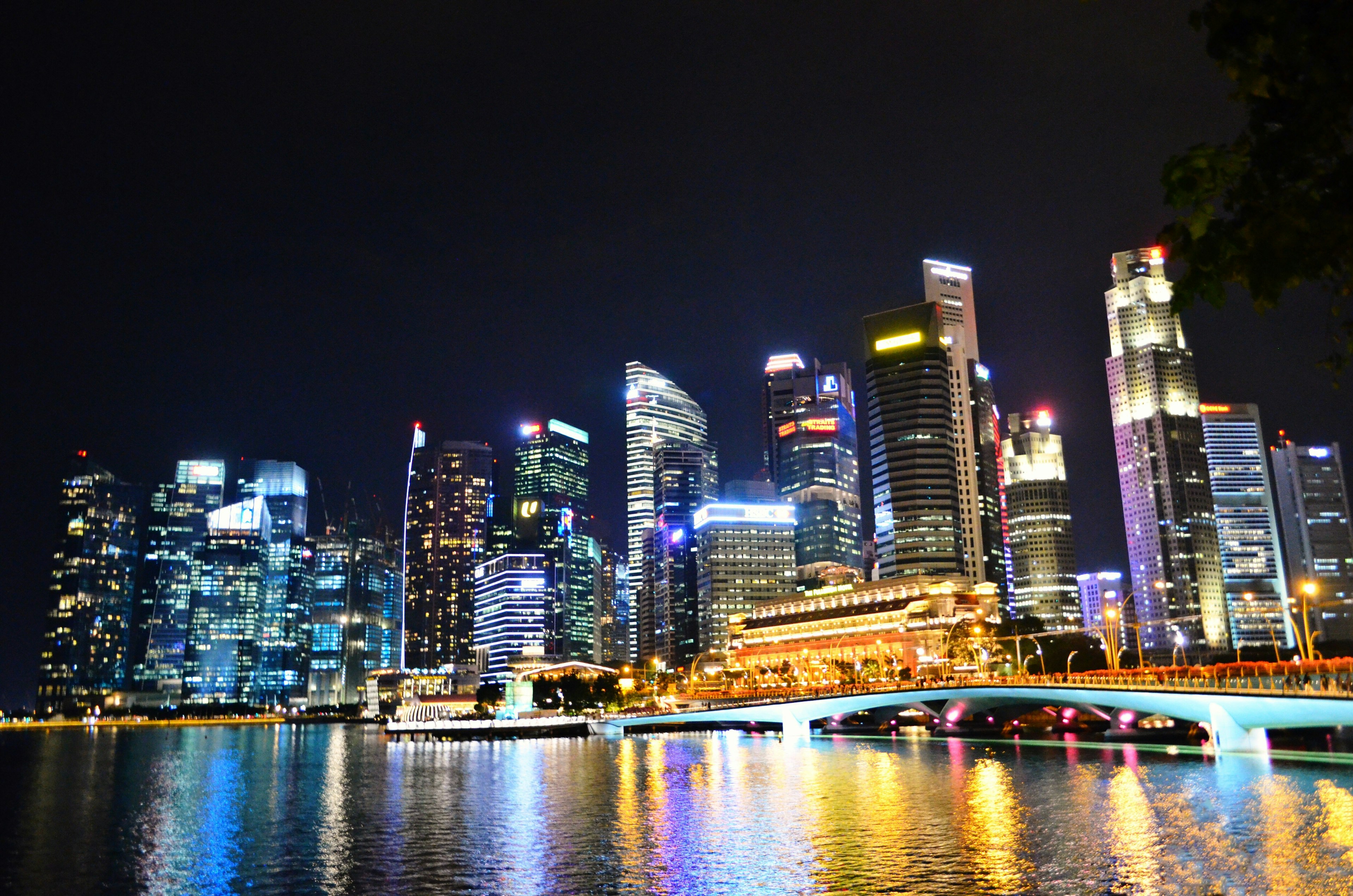 Singapore skyline at night featuring illuminated skyscrapers and reflections on the water