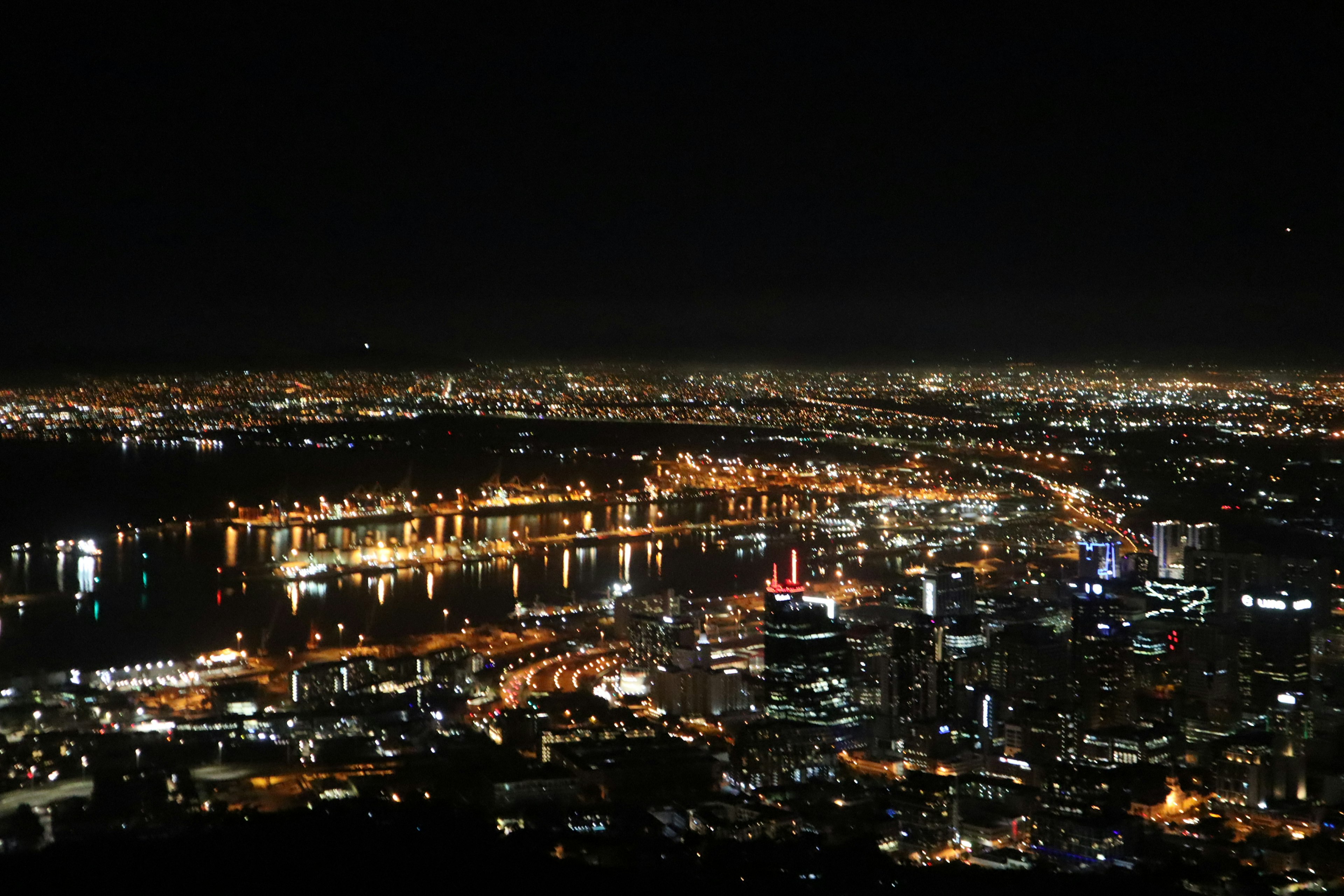 Night cityscape featuring illuminated buildings and river reflections