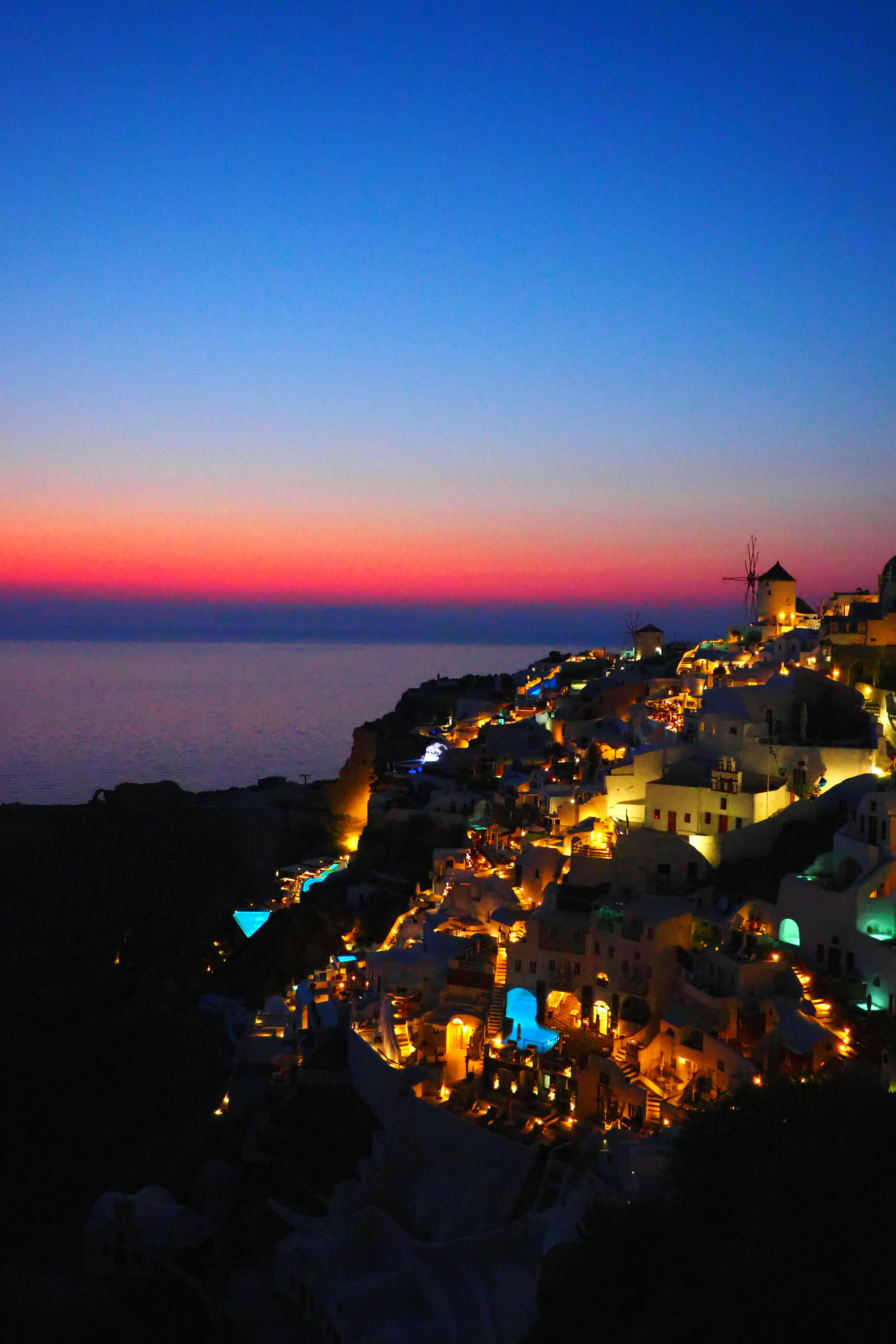 Beleuchtete Häuser von Santorin vor einem schönen Sonnenuntergangshimmel und dem Meer