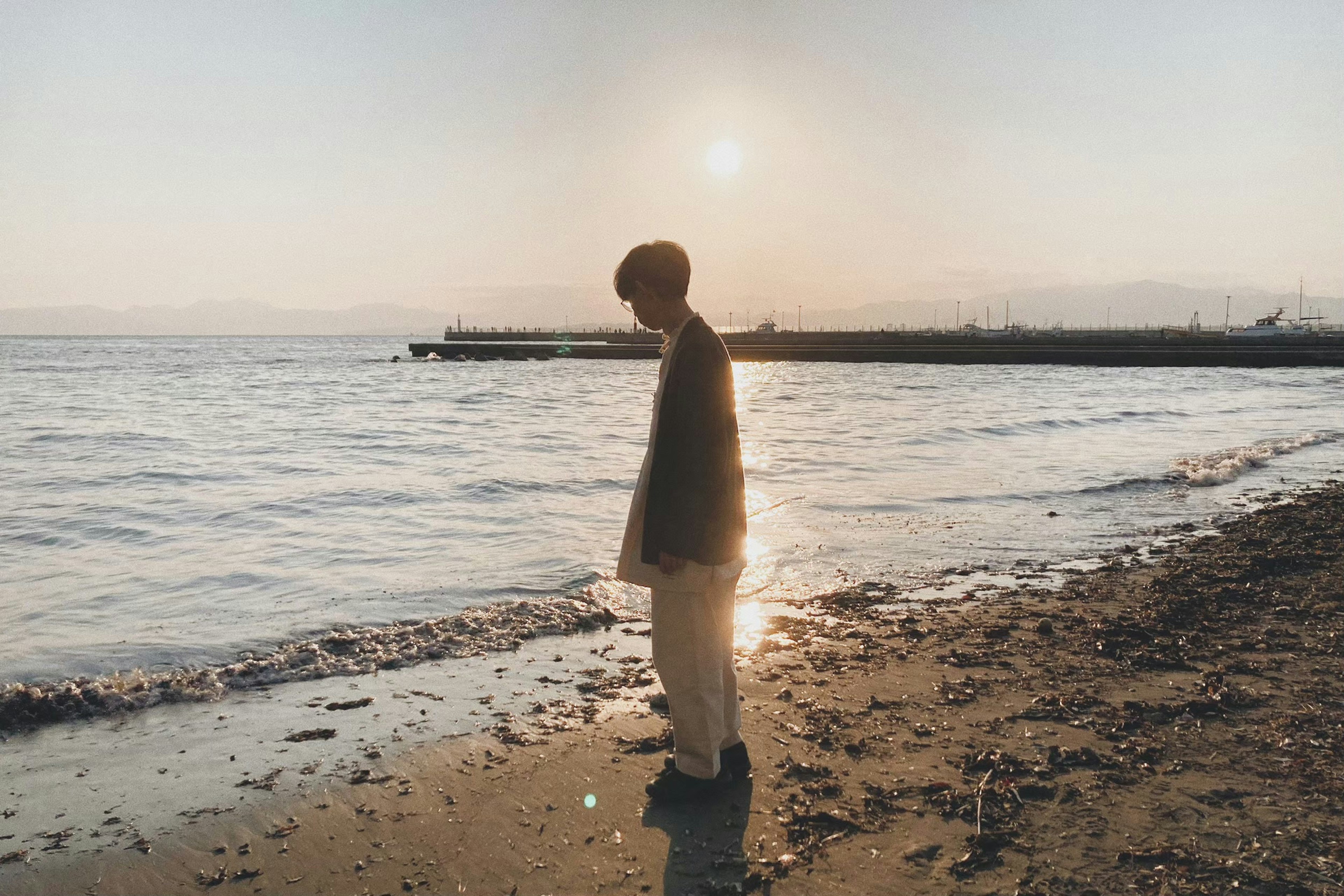 Silhouette di un uomo in piedi sulla spiaggia con il tramonto sullo sfondo