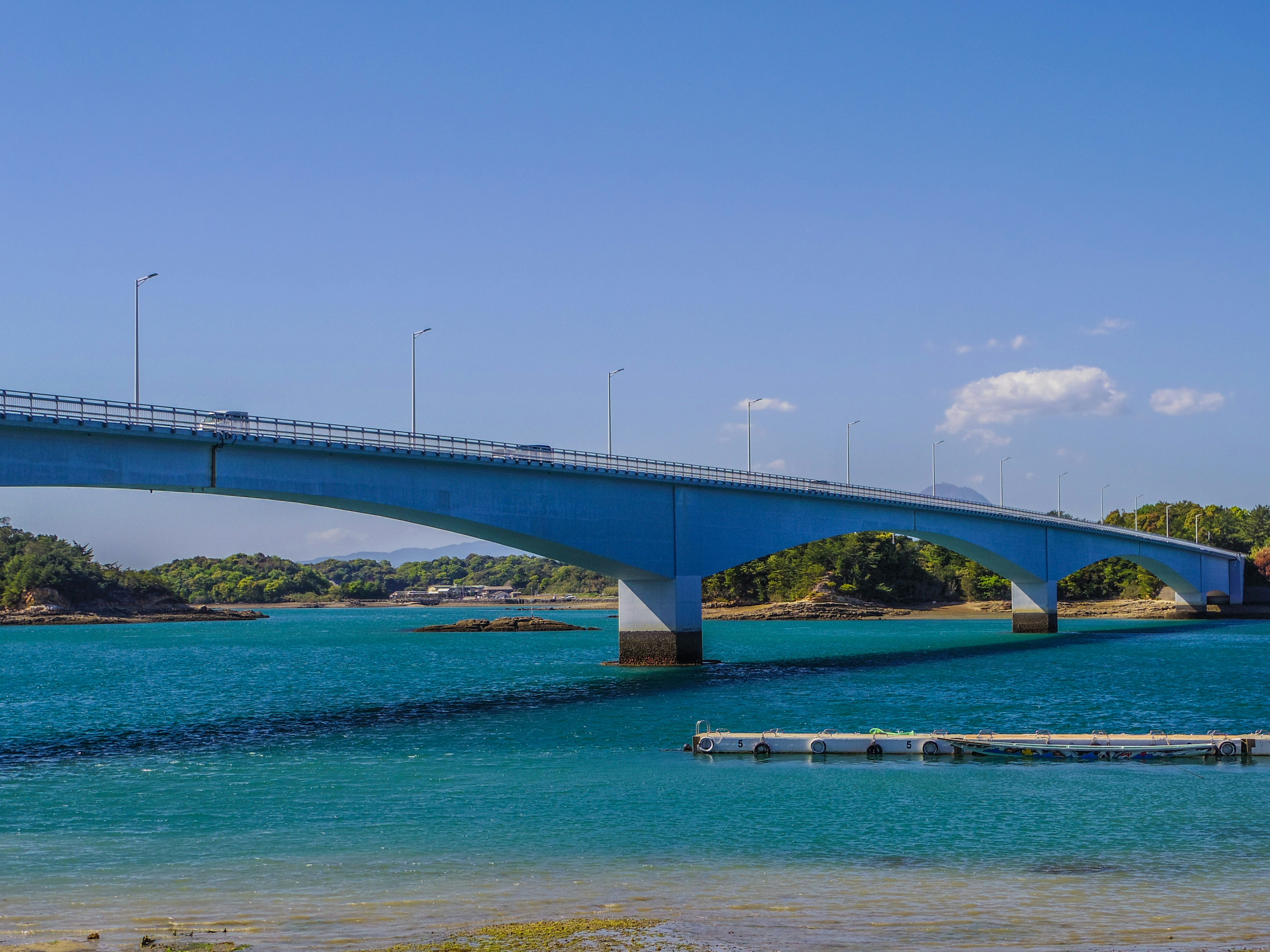 A blue bridge spanning over turquoise water