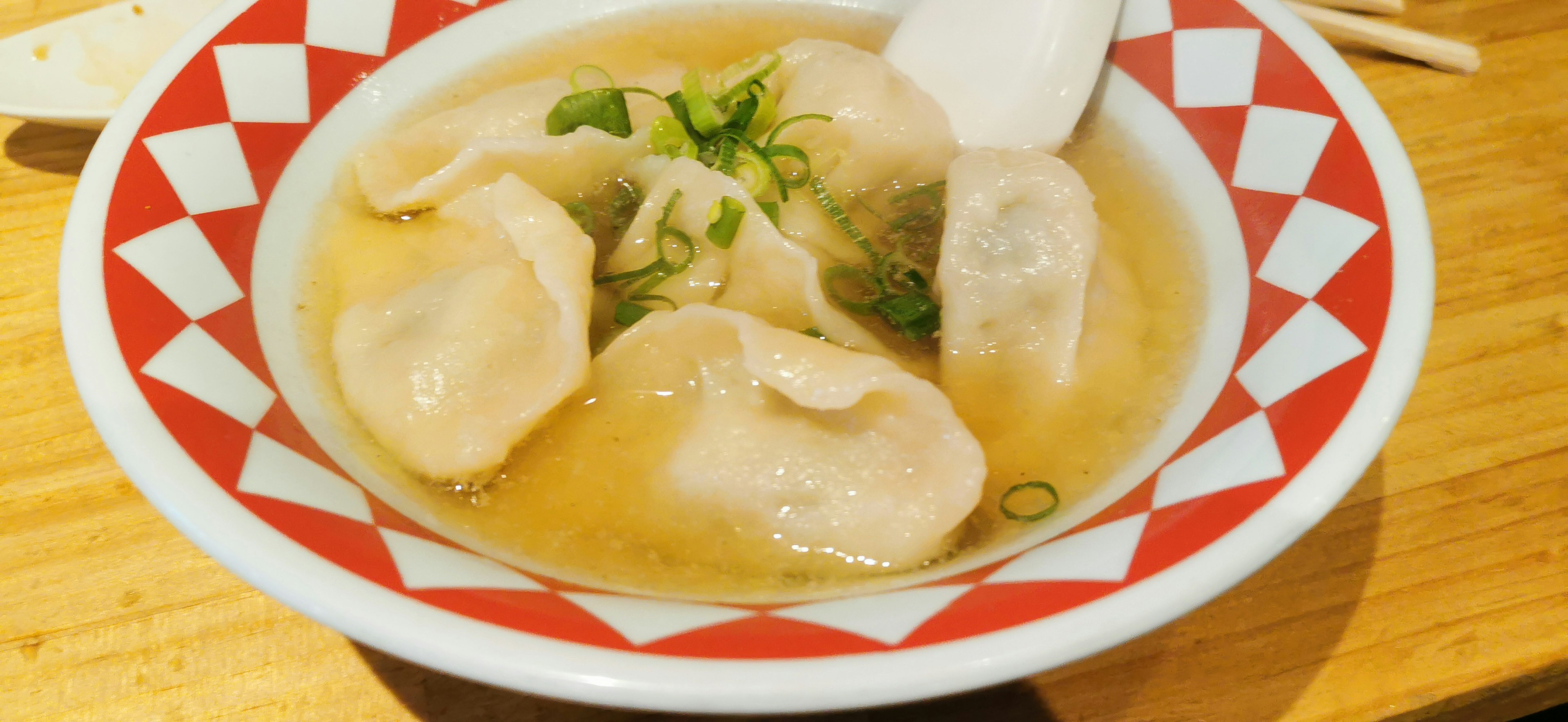 Raviolis dans un bouillon servis dans un bol à motifs rouges et blancs