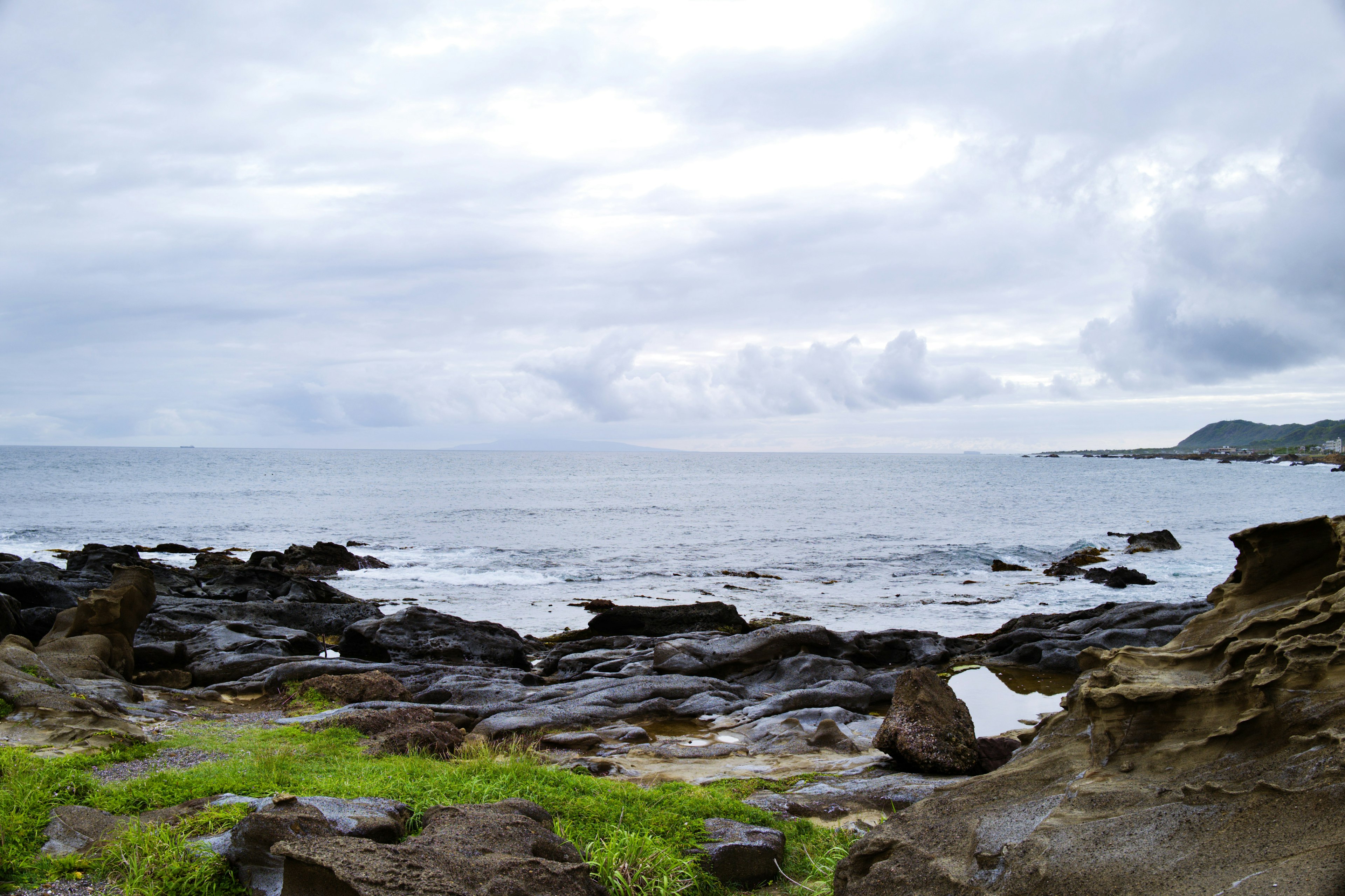 Pemandangan pantai dengan garis pantai berbatu dan rumput hijau