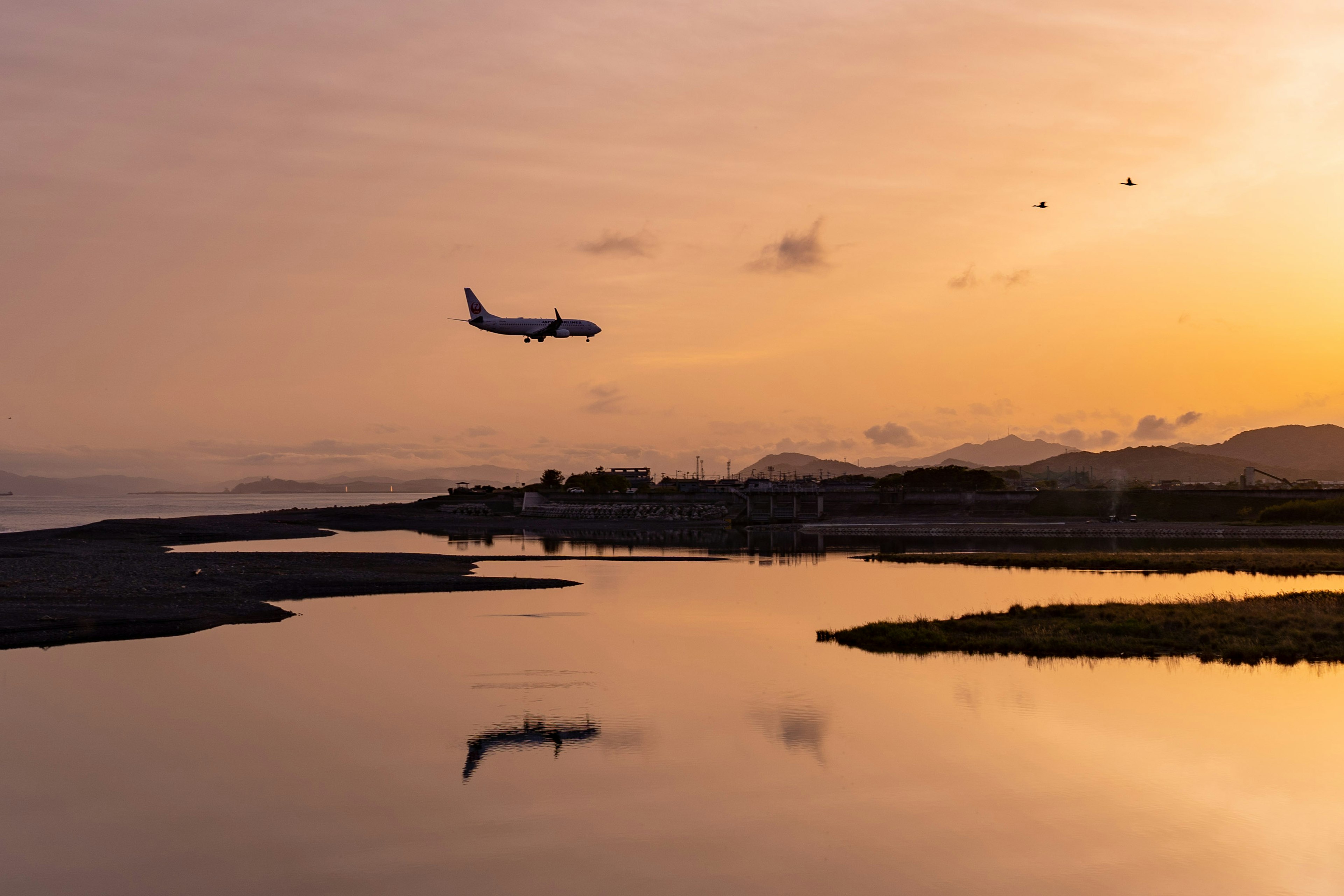 夕焼けの空に飛行機が着陸する風景 河川の反射が美しい