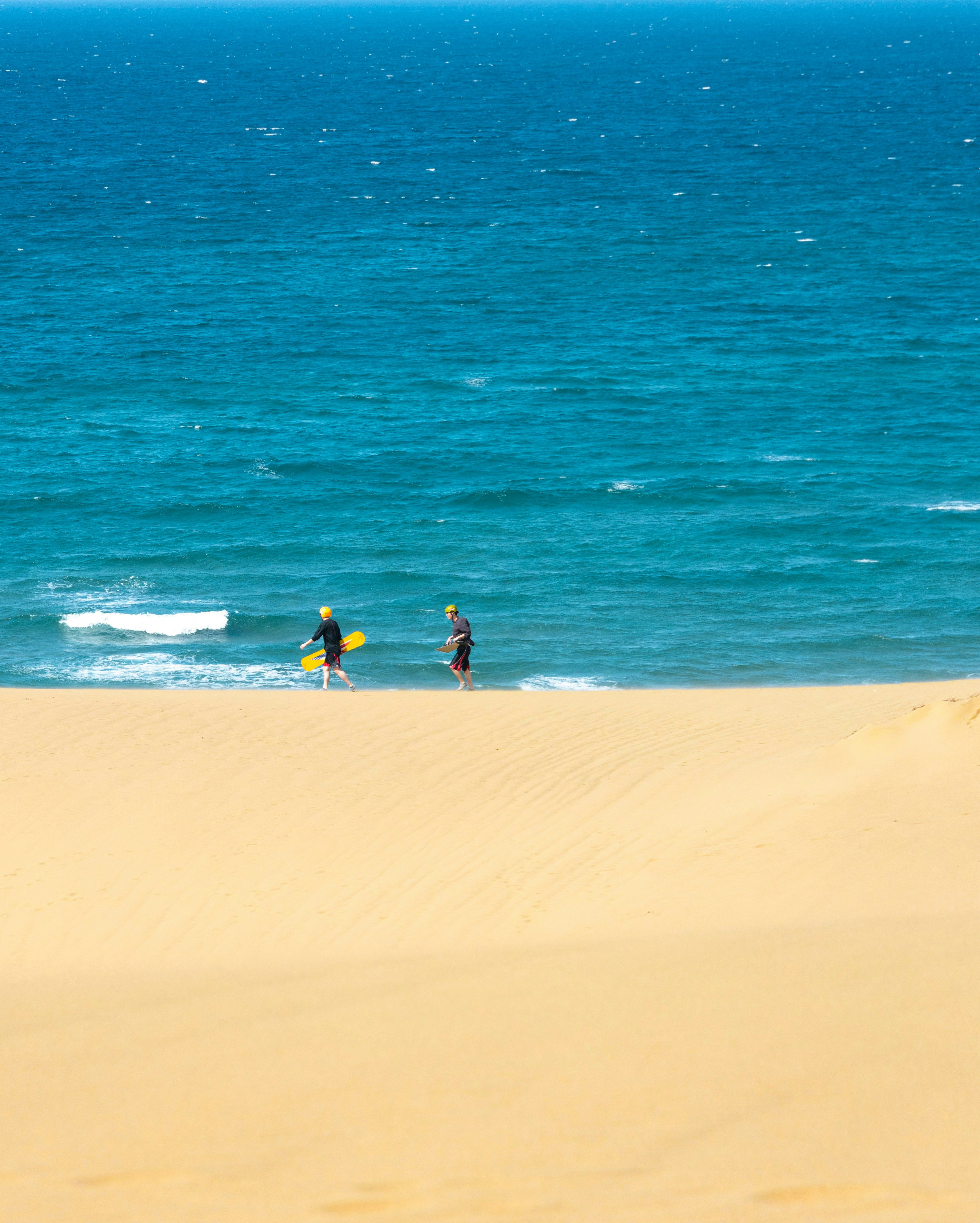 Deux surfeurs sur une dune de sable surplombant l'océan bleu