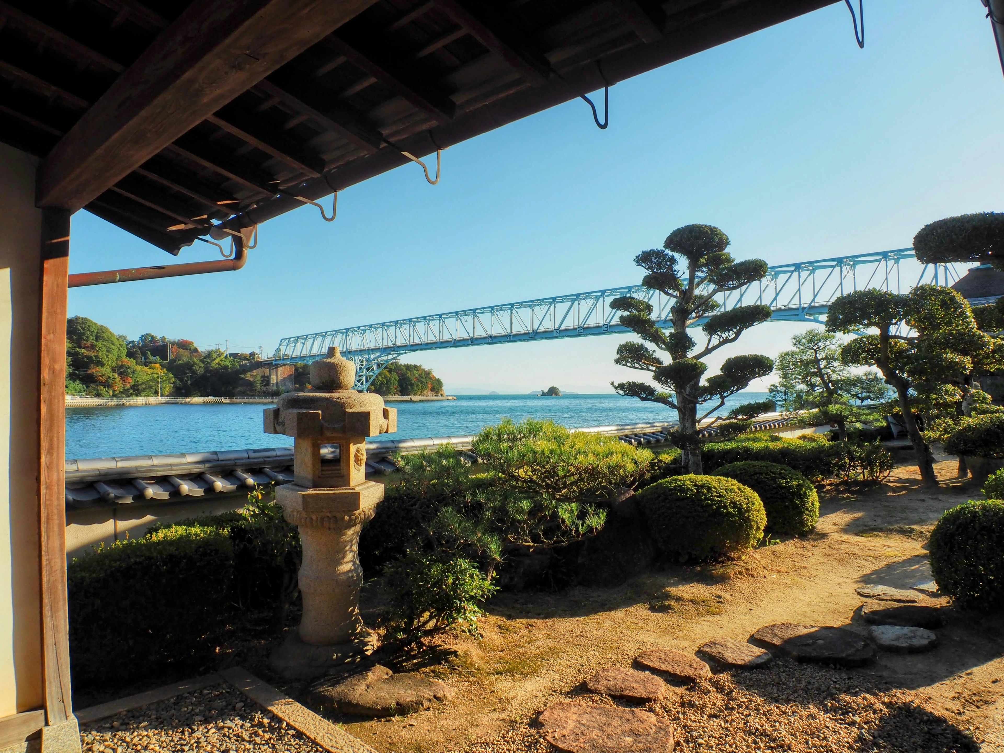 Vista escénica de un jardín con un puente y una linterna de piedra