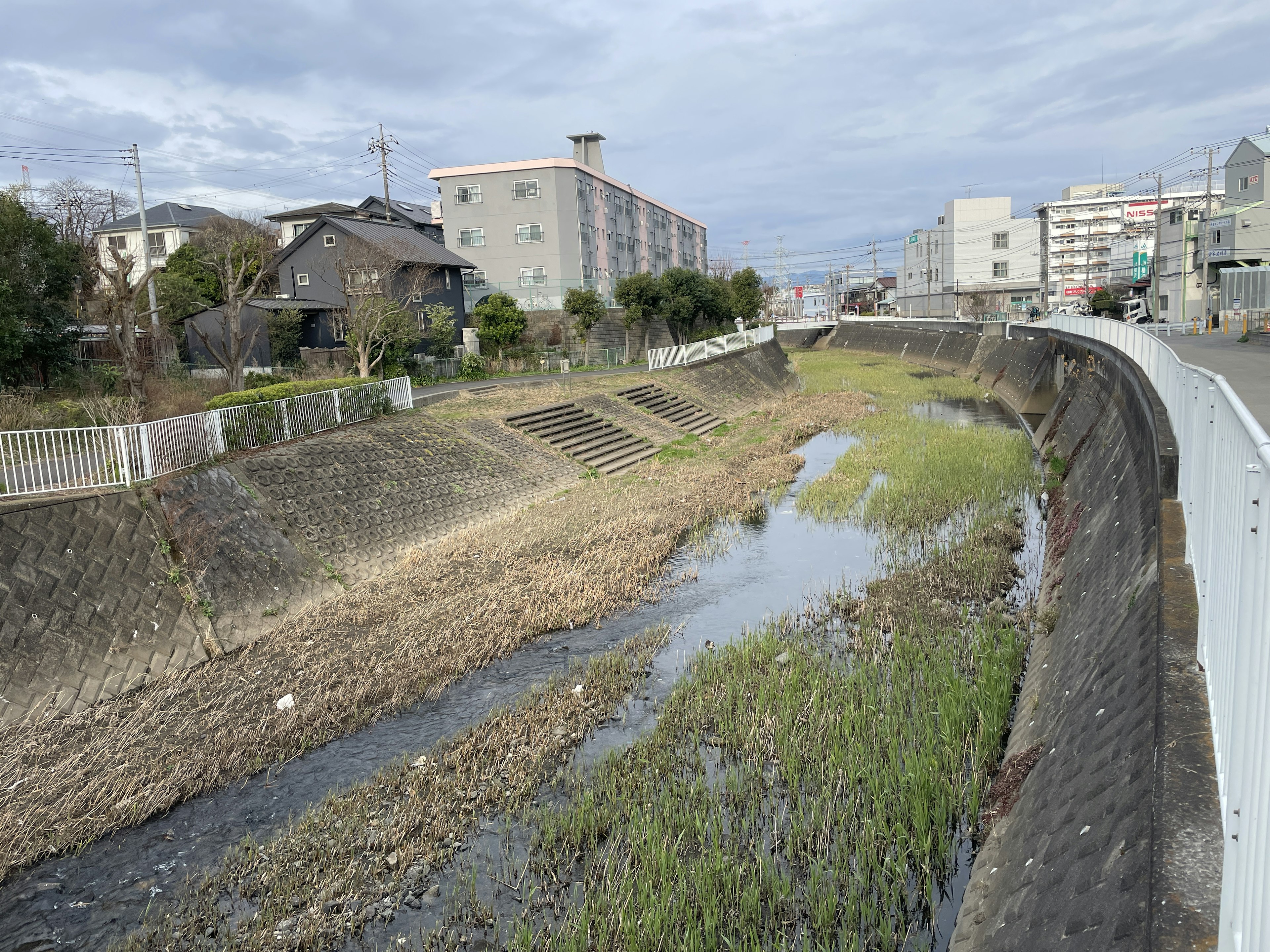 Lecho de río seco con vegetación escasa junto a edificios