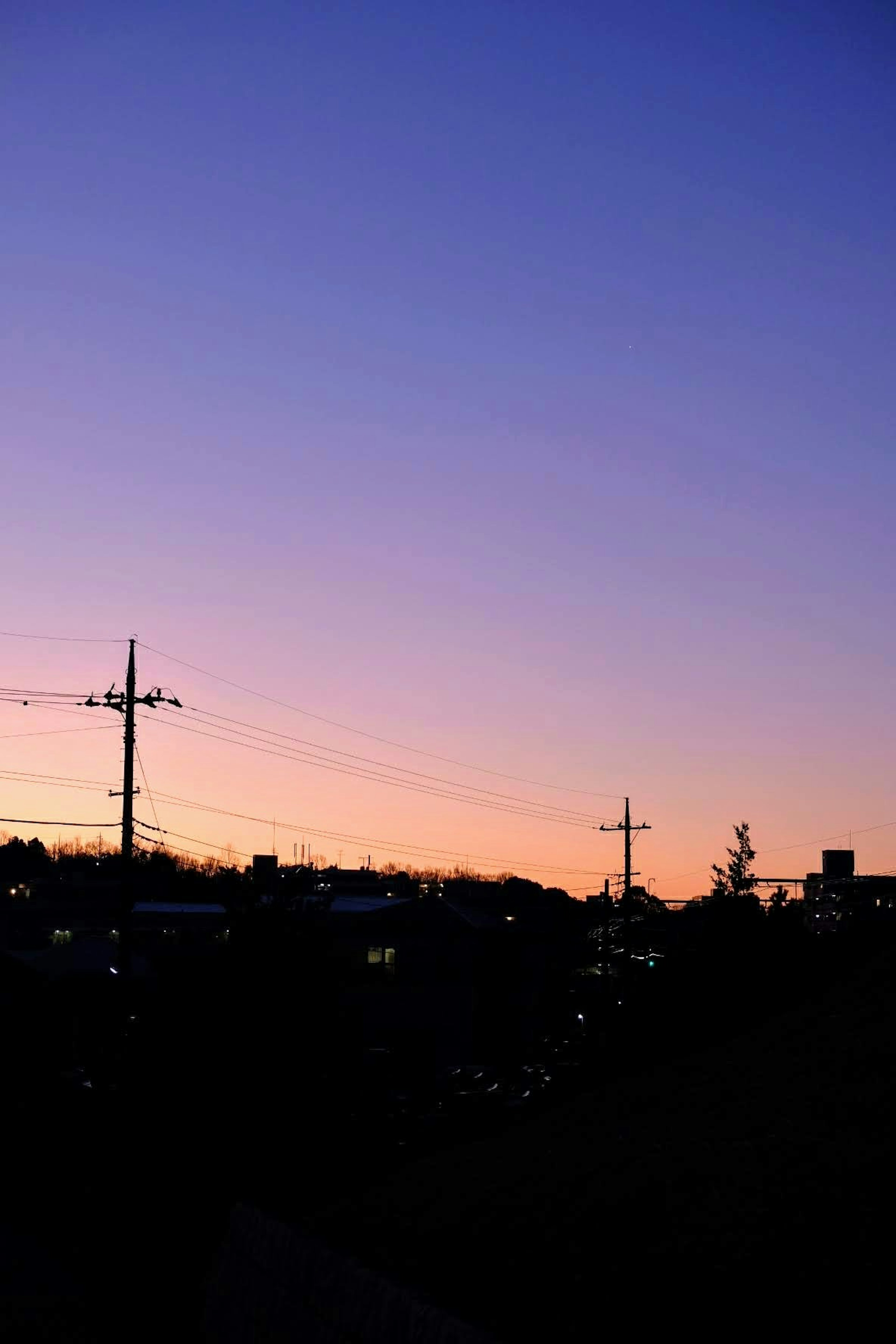 夕焼けの空とシルエットの電柱が見える風景