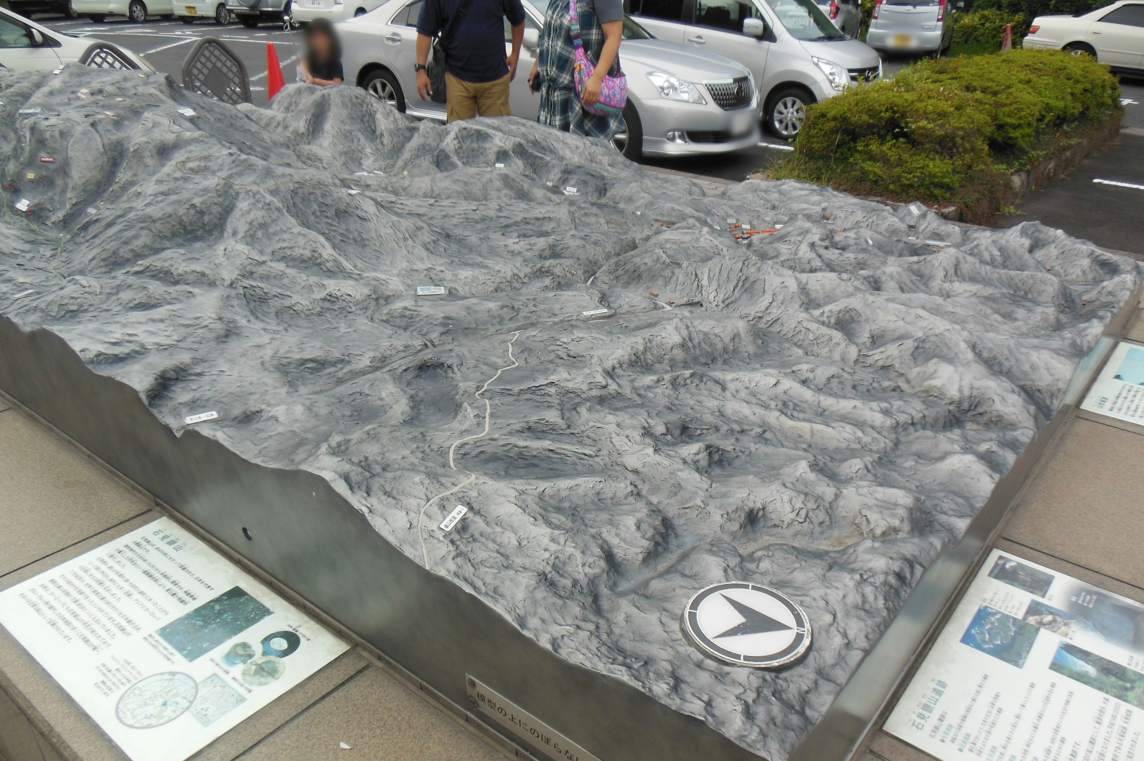 詳細な地形模型が展示されている風景 駐車場に立つ人々