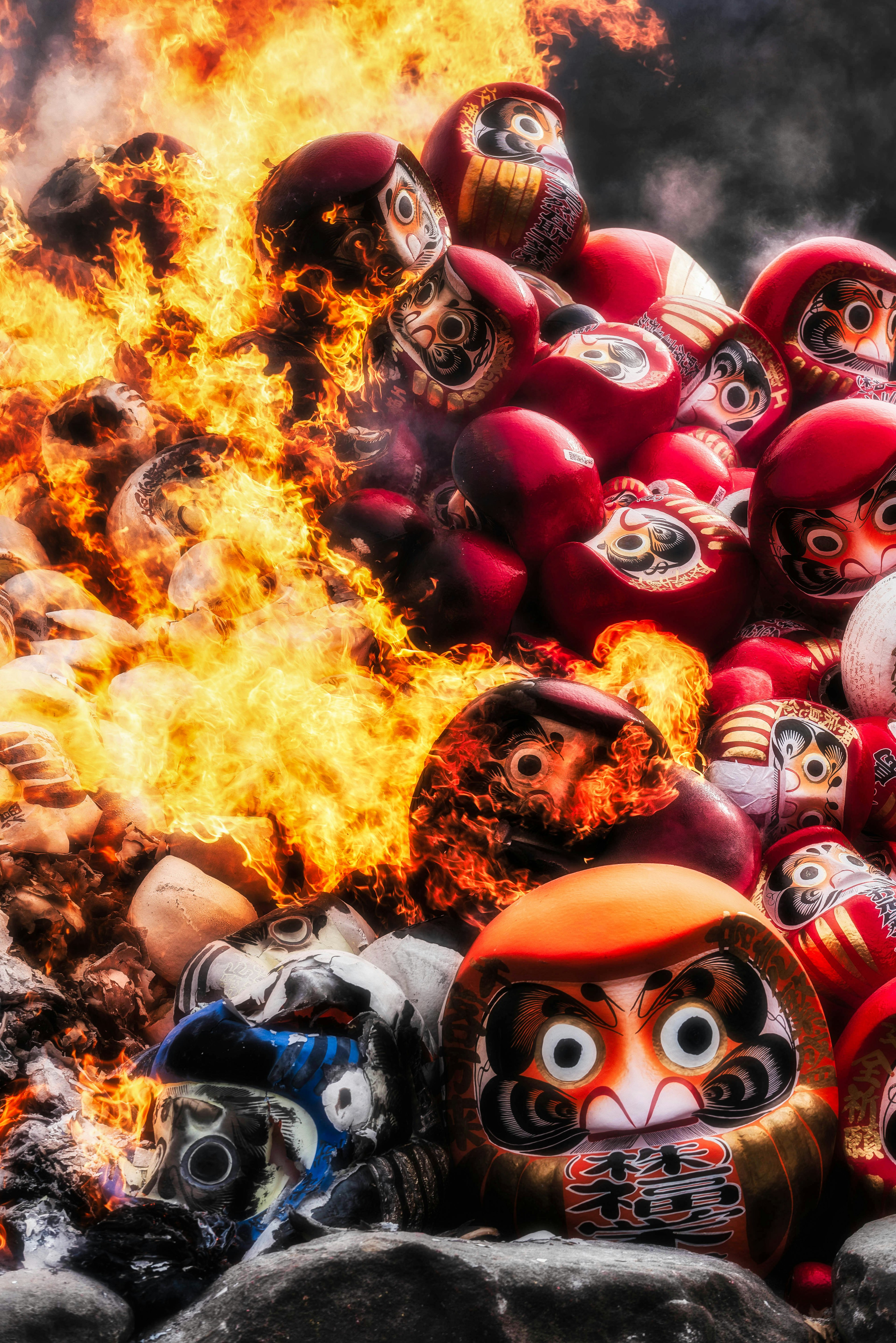 A pile of burning Daruma dolls with flames