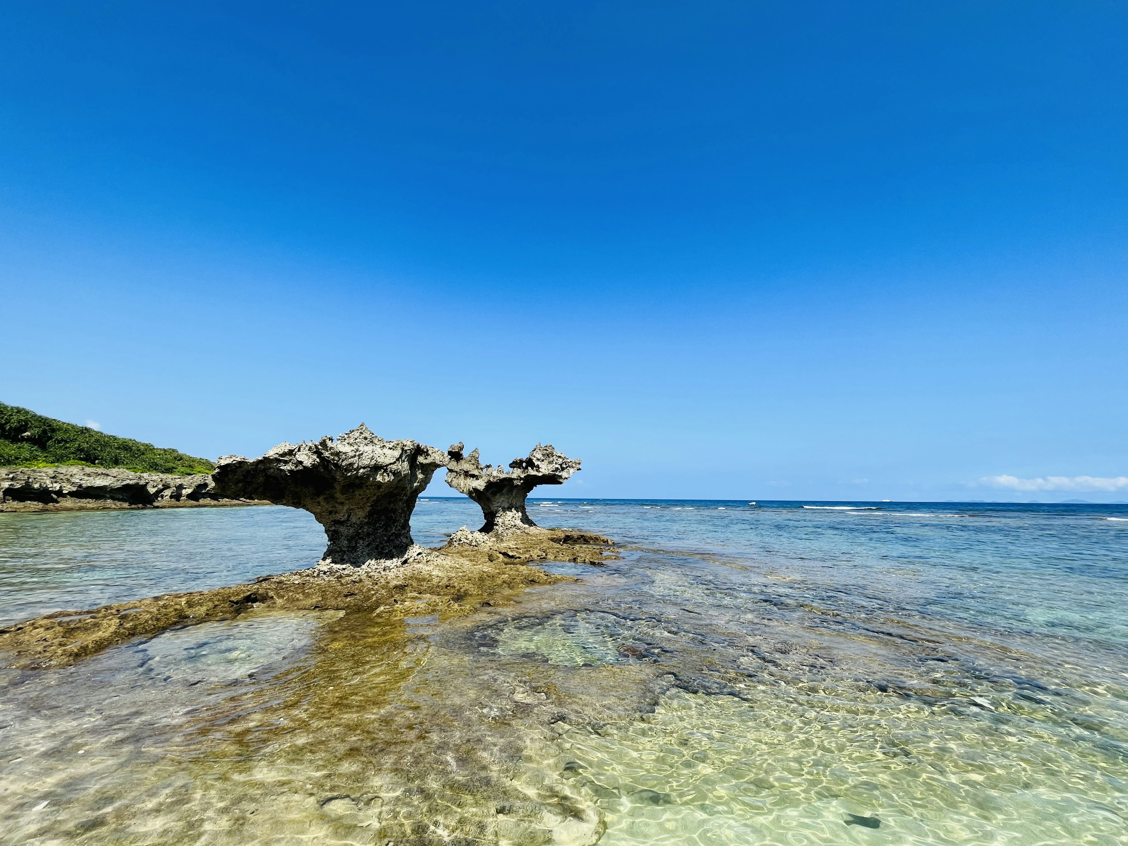 Paesaggio con formazioni rocciose che emergono da acque cristalline sotto un cielo blu