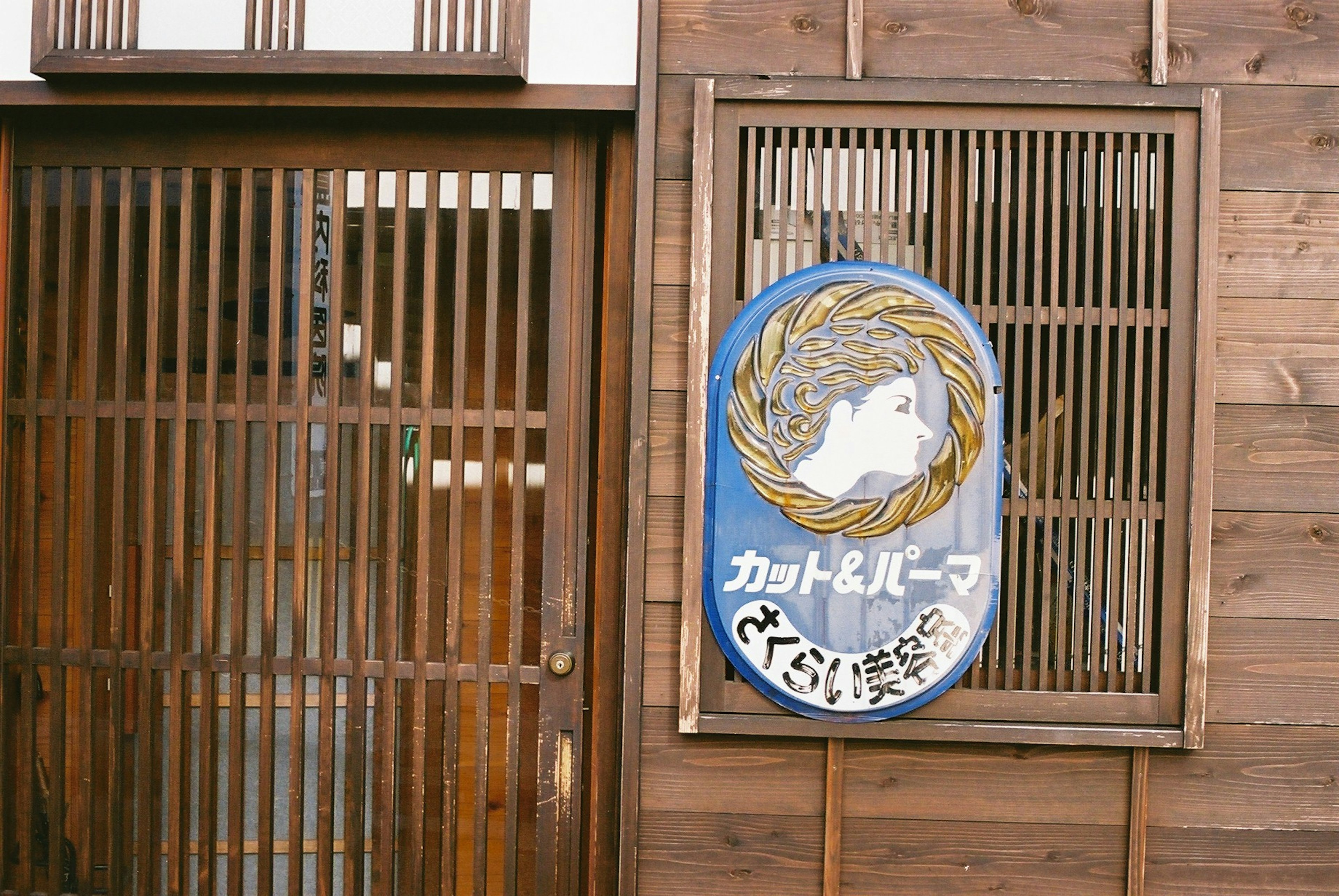 木製の店舗の外観にある看板とスラットのドア