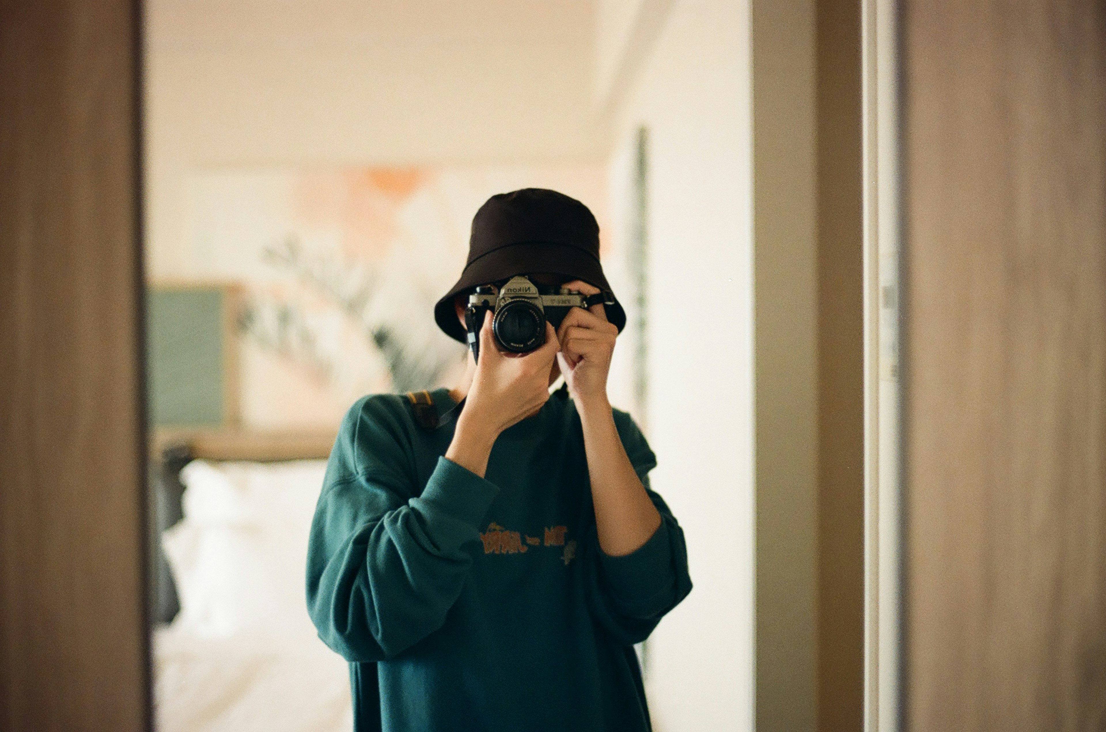 Personne tenant un appareil photo devant un miroir dans une pièce