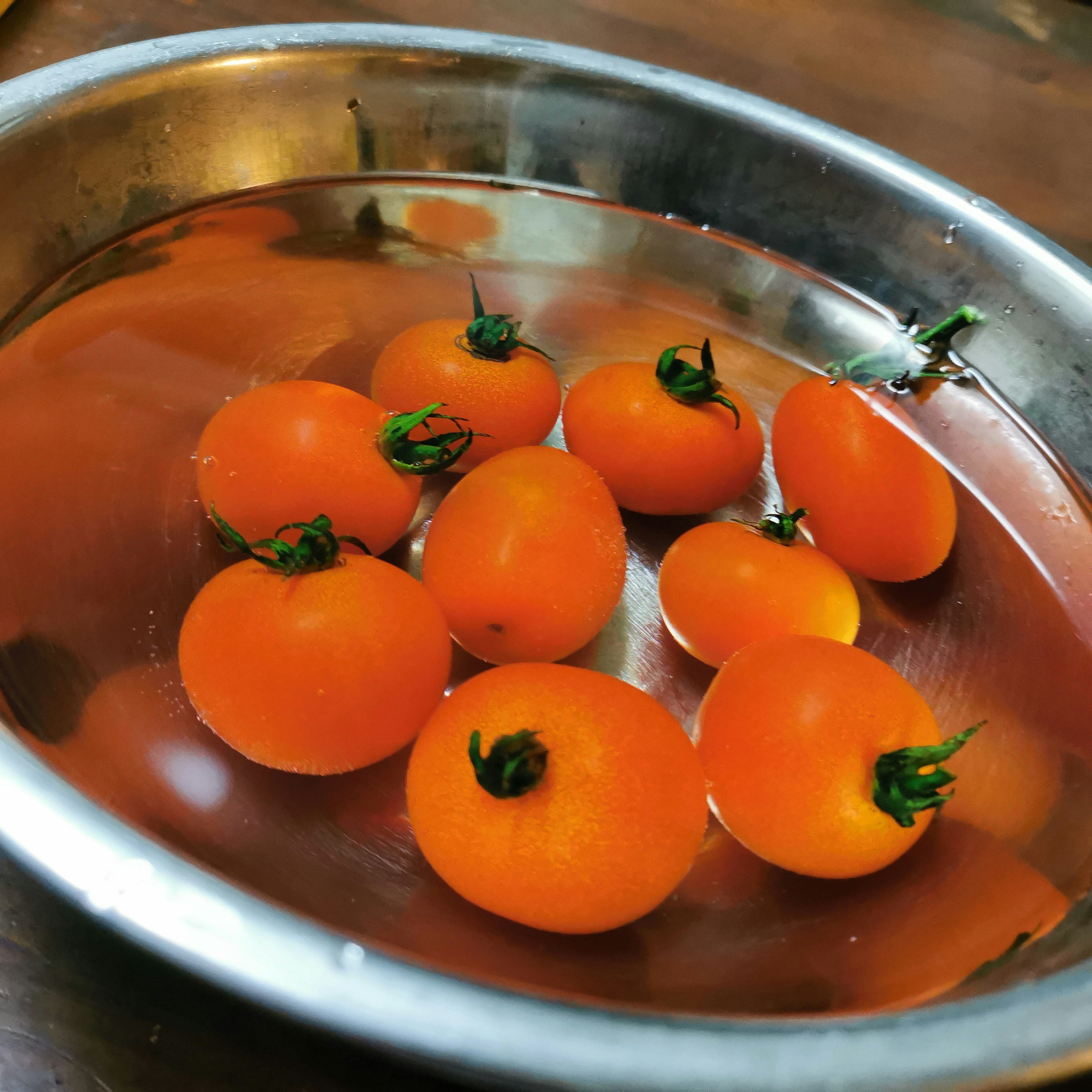 Eine Schüssel mit kleinen orangefarbenen Tomaten, die im Wasser schwimmen