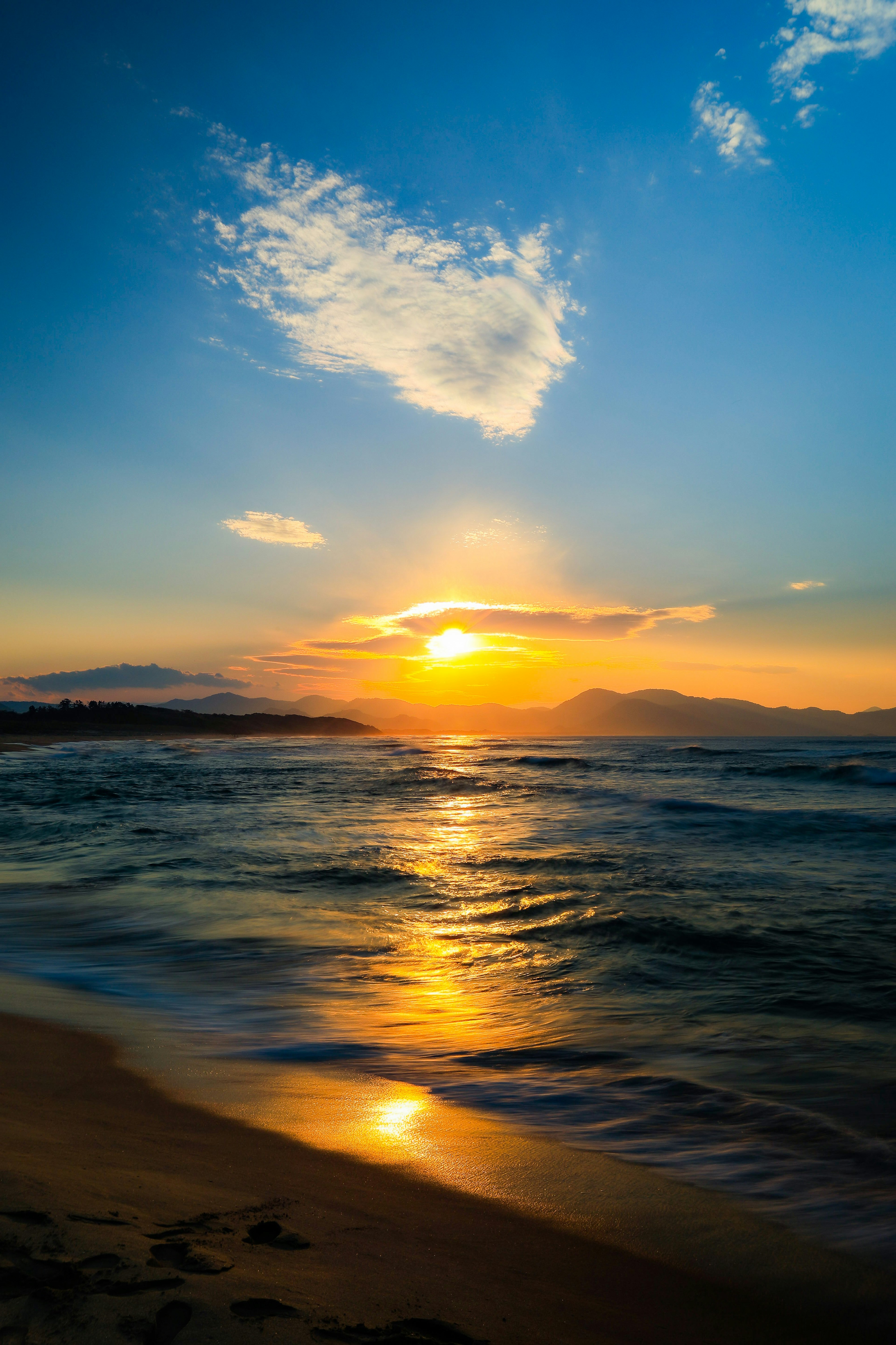 夕日が海に沈む美しい風景青い空と雲のコントラスト