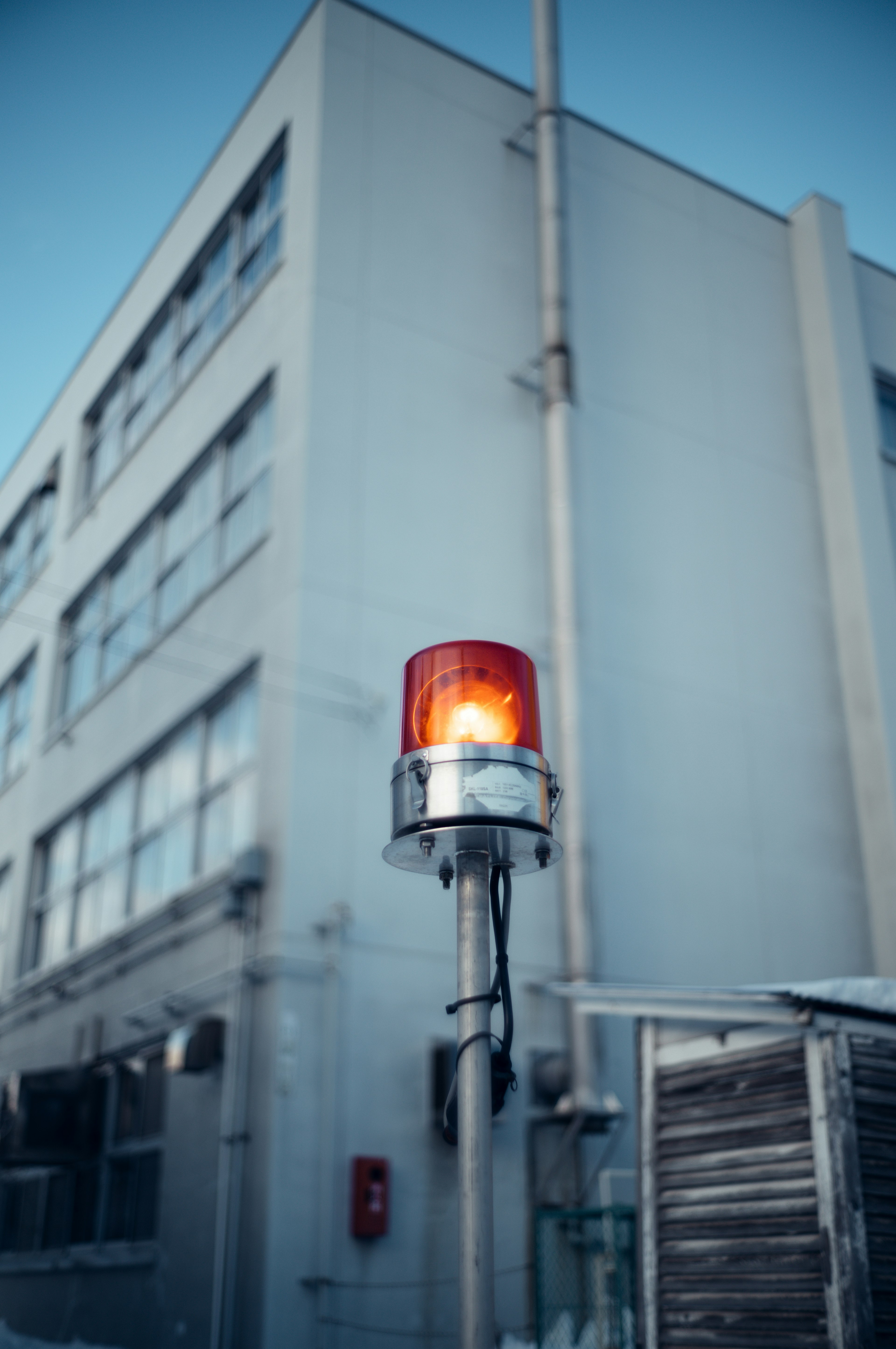 Una luce rossa lampeggiante su un palo davanti a un edificio